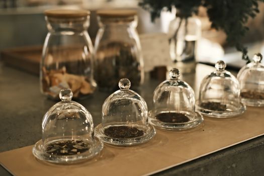 Elegant glass display jars with herbs in a warm, rustic cafe ambiance.