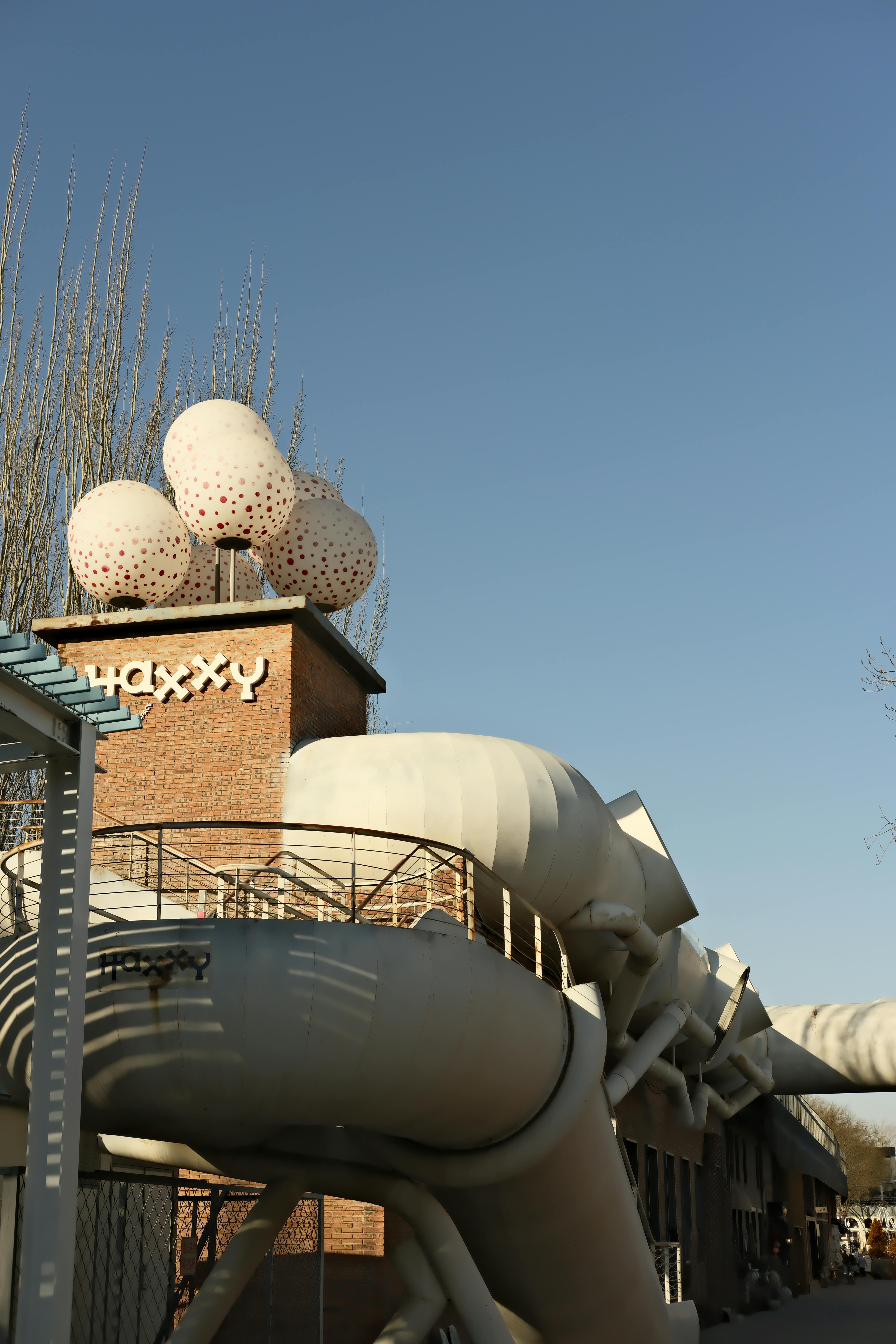 бесплатная Промышленное здание с художественной крышей на фоне чистого голубого неба. Стоковое фото