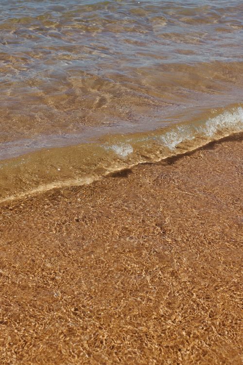 Free Peaceful ocean wave gently washing over golden sandy beach, capturing tranquility and natural beauty. Stock Photo