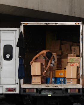 Delivery worker loads boxes onto a truck, illustrating shipping and logistics.