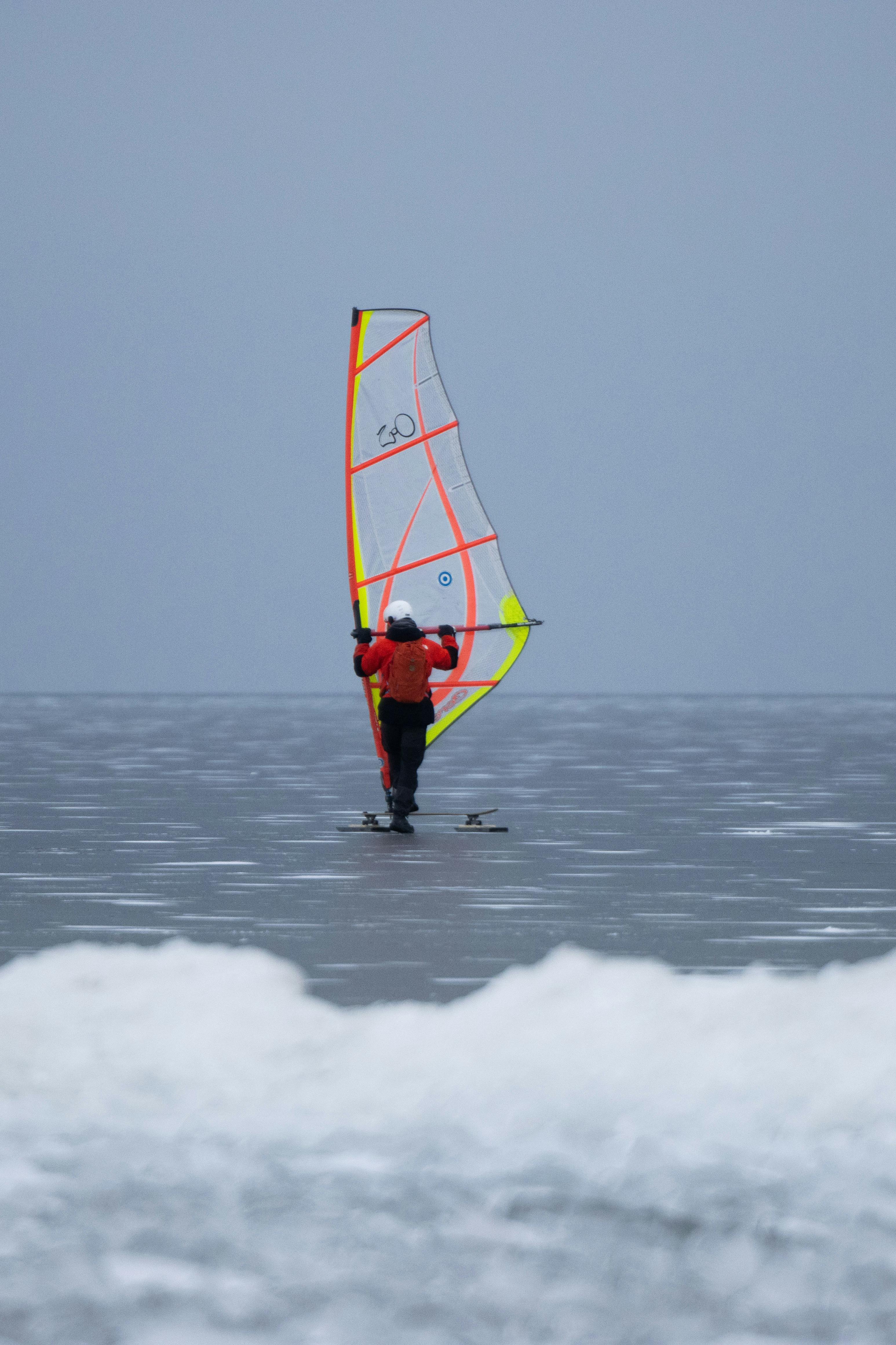 Kostenlos Ein Mann segelt auf einem zugefrorenen See in Jönköping, Schweden, und demonstriert damit winterliche Abenteuersportarten. Stock-Foto