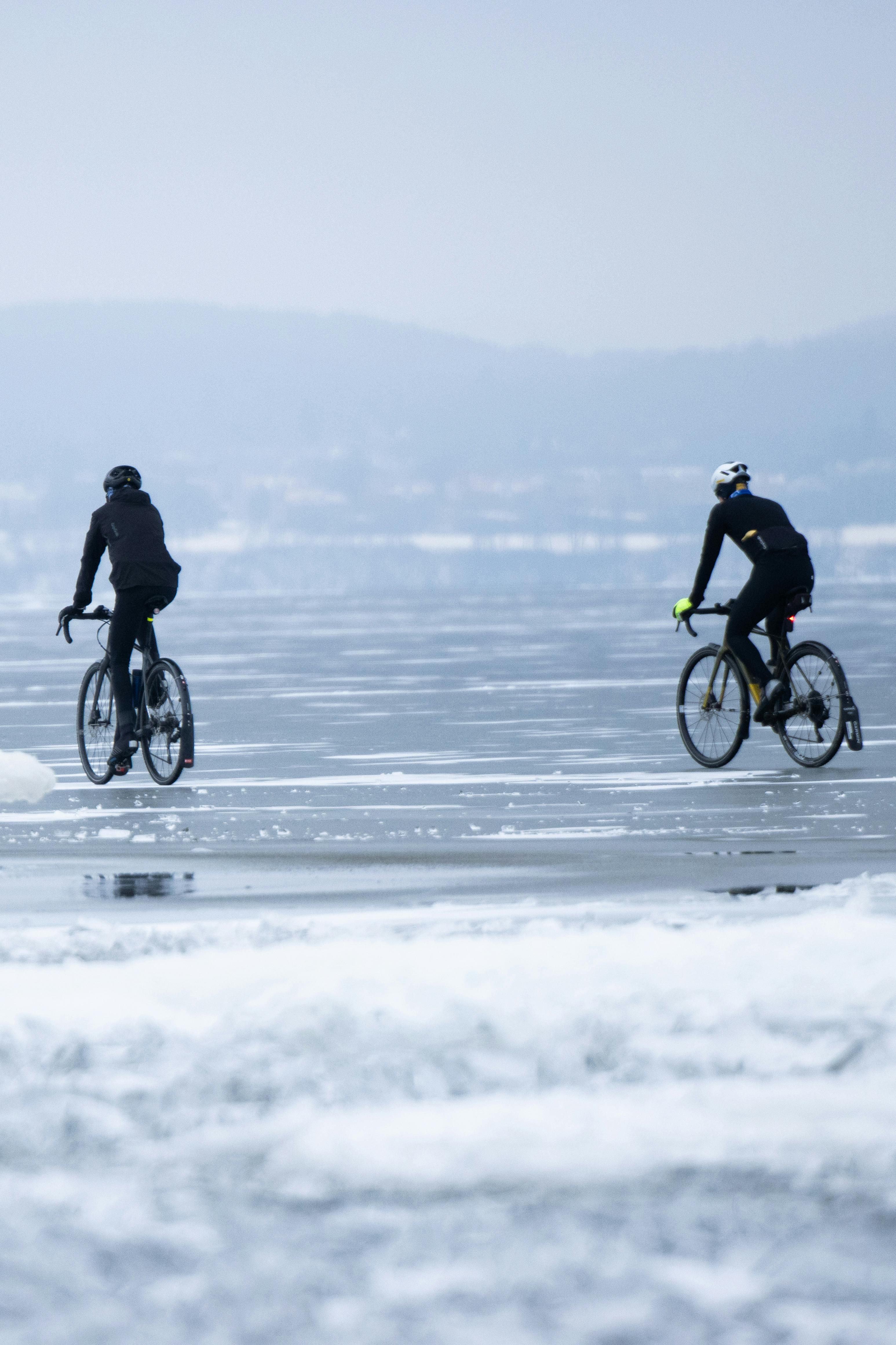 Kostenlos Zwei Radfahrer auf einem zugefrorenen See in Jönköping – ein winterliches Abenteuer. Stock-Foto