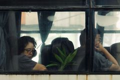 Two people sit inside a bus, viewed through a window, exuding a contemplative mood.