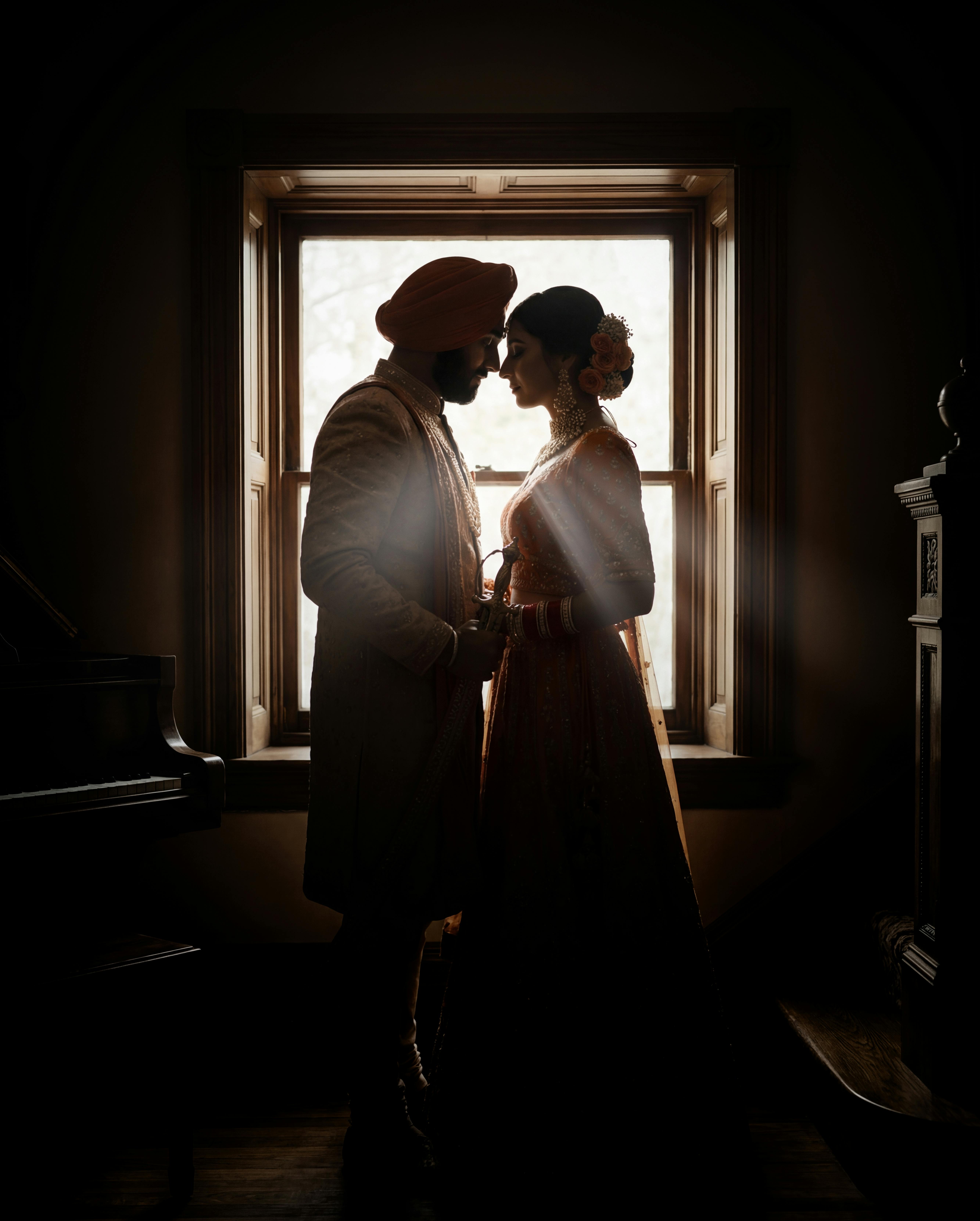 Kostenlos Eine romantische Silhouette eines Paares in traditioneller Kleidung, das einen zärtlichen Moment am Fenster teilt. Stock-Foto
