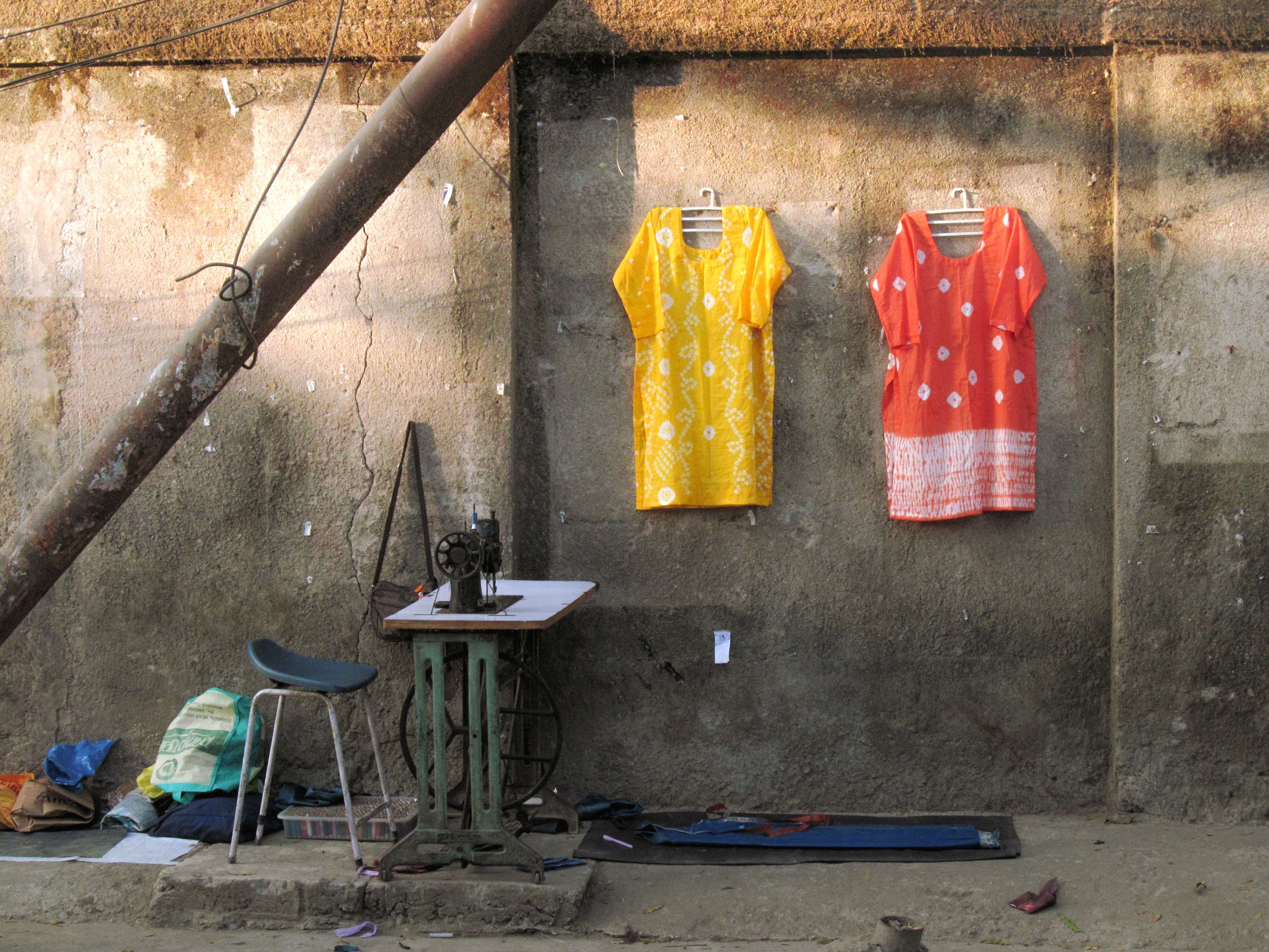 A vintage sewing machine with a half-finished dress, surrounded by fabric scraps and old photographs