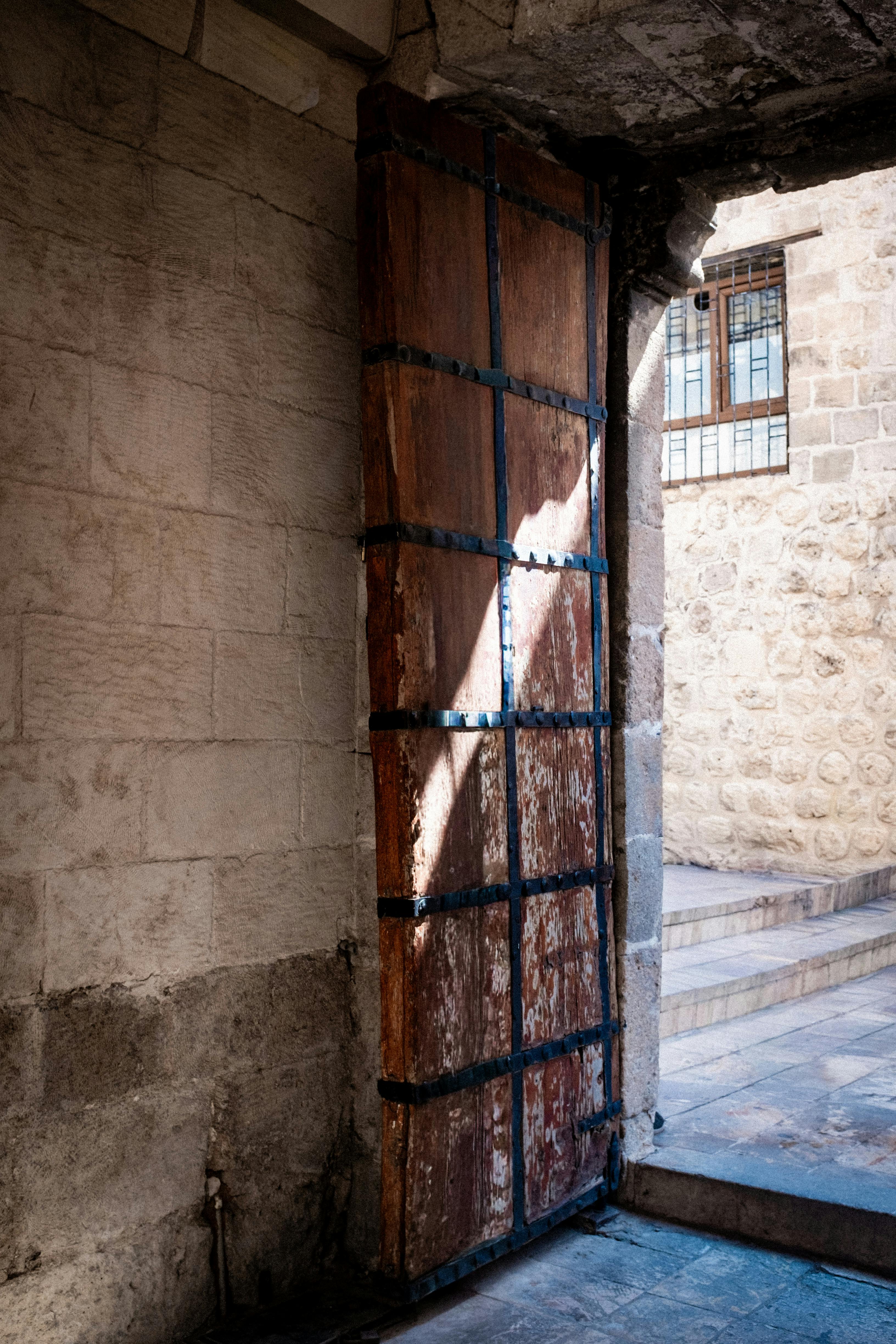 Δωρεάν Ρουστίκ ξύλινη πόρτα στην είσοδο ενός παλιού πέτρινου κτιρίου, που αποτυπώνει την ιστορική γοητεία. Φωτογραφία από στοκ φωτογραφιών