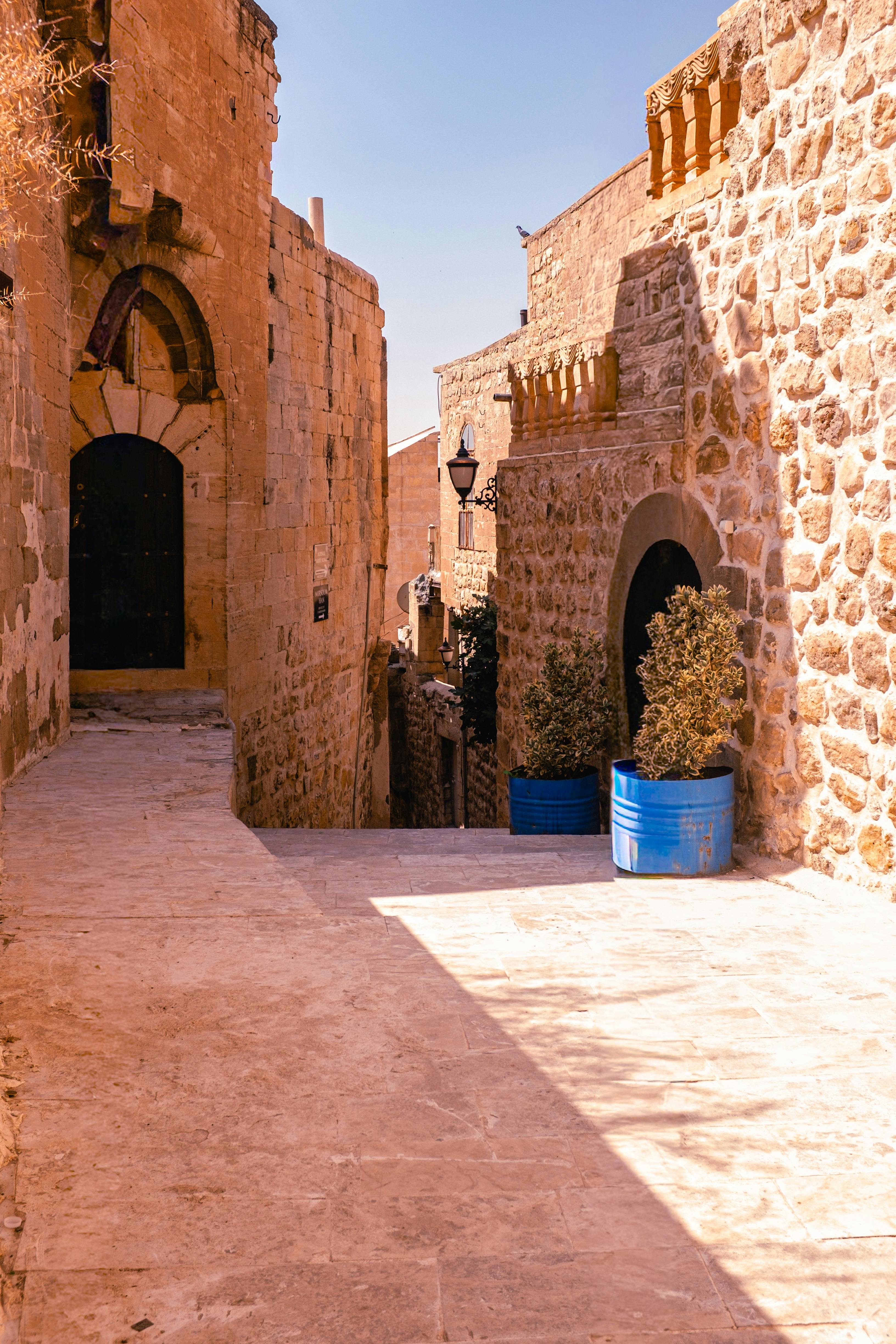 Δωρεάν Εξερευνήστε ένα ηλιόλουστο αρχαίο σοκάκι με πέτρινους τοίχους και ιστορική αρχιτεκτονική. Φωτογραφία από στοκ φωτογραφιών