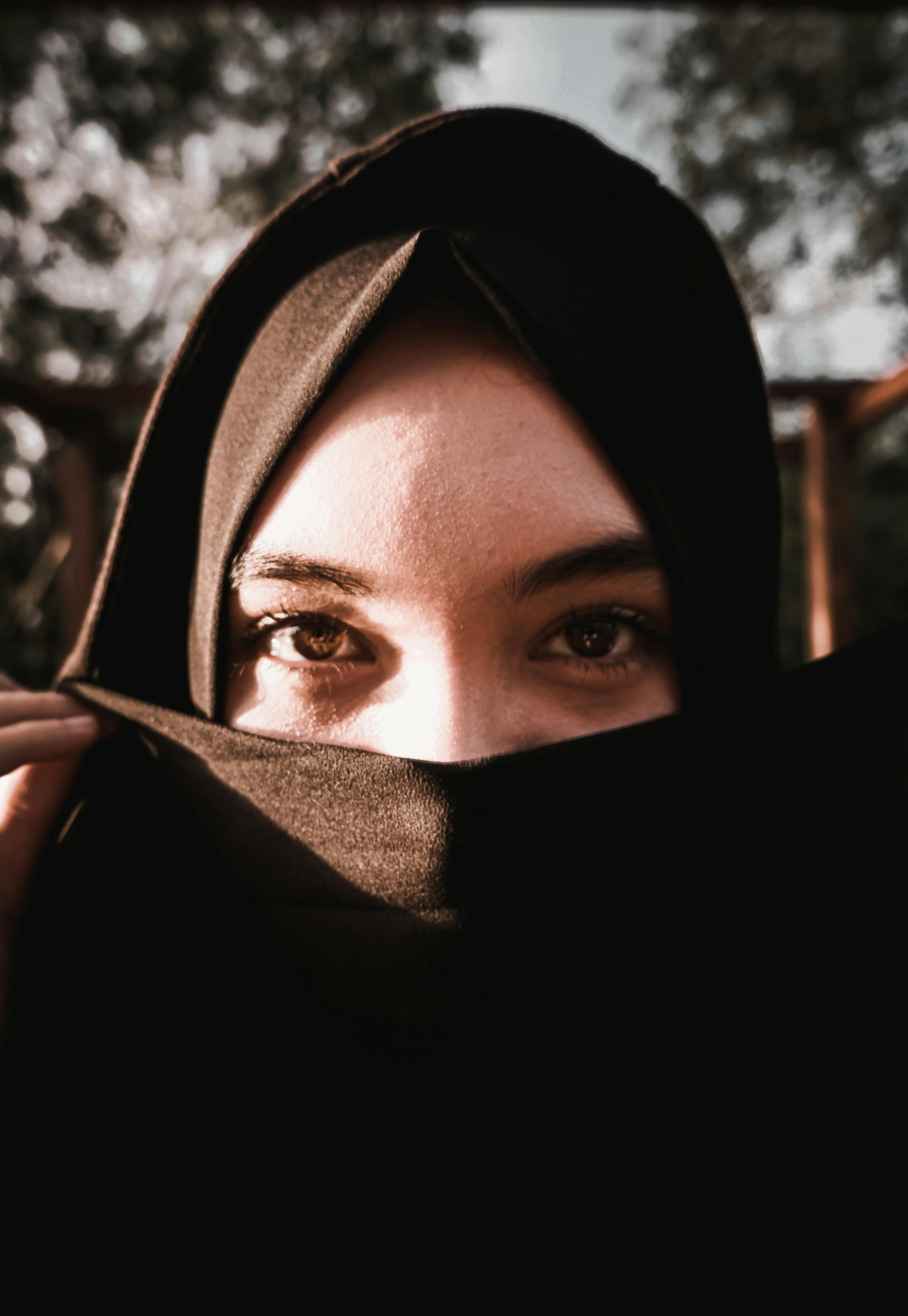 一幅迷人的肖像中，一位戴黑色头巾的女人正凝视着阳光，她的眼睛富有表现力