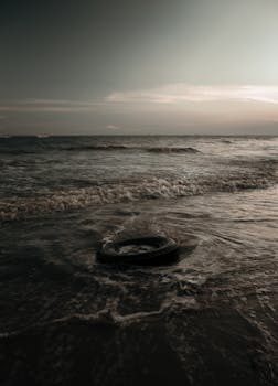 黄昏时分，海边的一个轮胎被海浪冲上岸，突显了环境问题