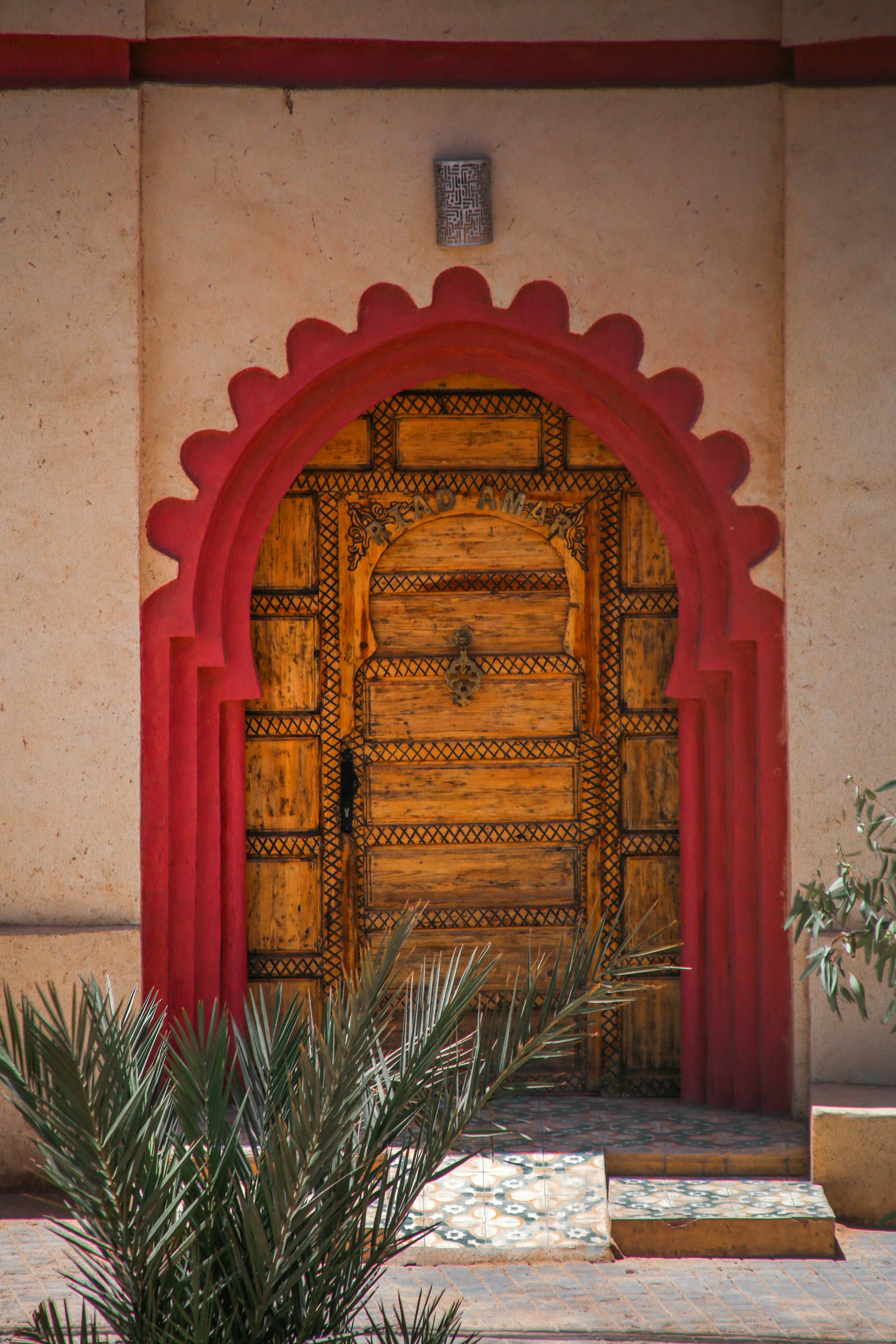 Δωρεάν Περίπλοκη ξύλινη πόρτα πλαισιωμένη από κόκκινη αψίδα, που αναδεικνύει τη μαροκινή αρχιτεκτονική. Φωτογραφία από στοκ φωτογραφιών