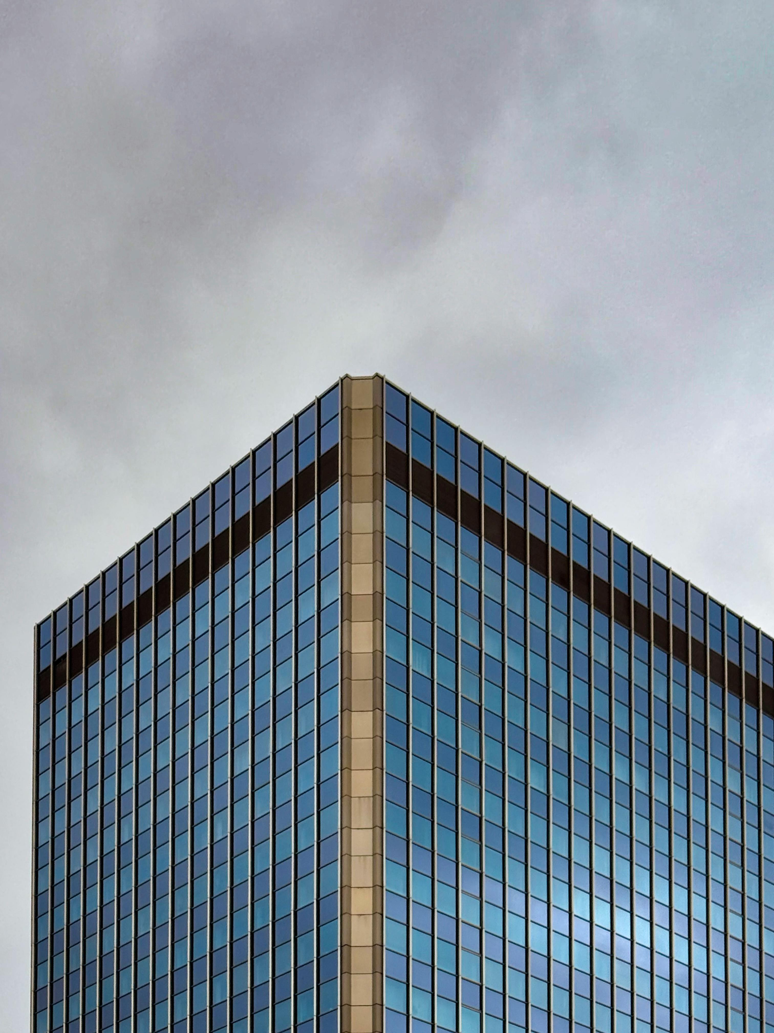 Δωρεάν Κομψή μοντέρνα γυάλινη πρόσοψη ενός ουρανοξύστη ενάντια σε έναν συννεφιασμένο ουρανό. Φωτογραφία από στοκ φωτογραφιών