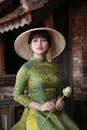 穿着传统服装的女人拿着花，戴着草帽，看起来很镇定