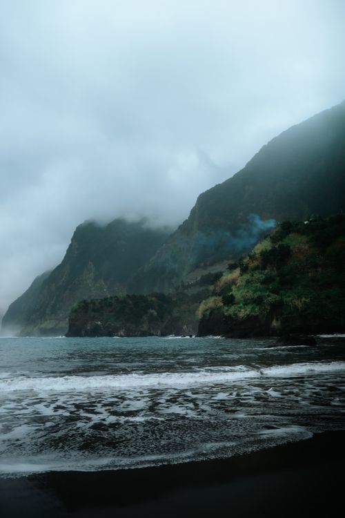 Free Moody coastal scene with misty mountains and ocean waves in Seixal, Portugal. Stock Photo
