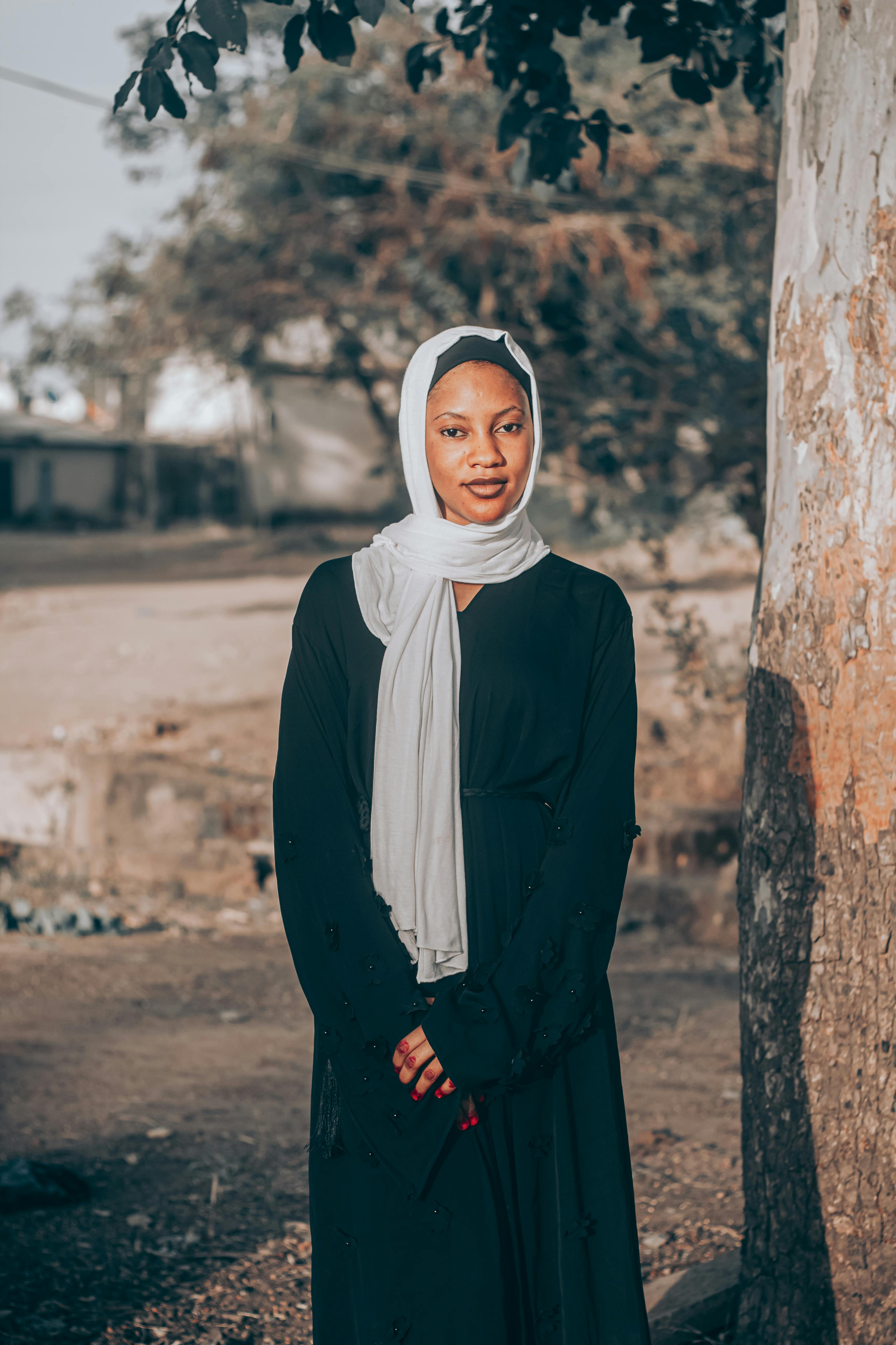 Gratis En kvinde i en traditionel hijab står udendørs ved et træ på en solskinsdag i Bauchi, Nigeria. Lagerfoto