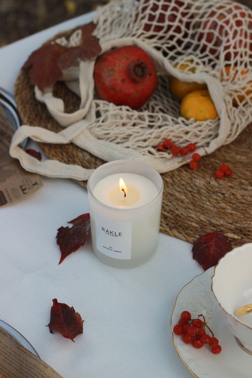 Free Cozy autumn setup with fruit, a net bag, and a lit candle on a rustic table. Stock Photo