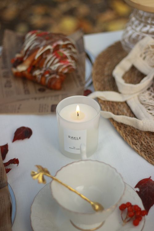 Free A warm autumn outdoor setup featuring a candle, coffee cup, and pastry on a table. Stock Photo