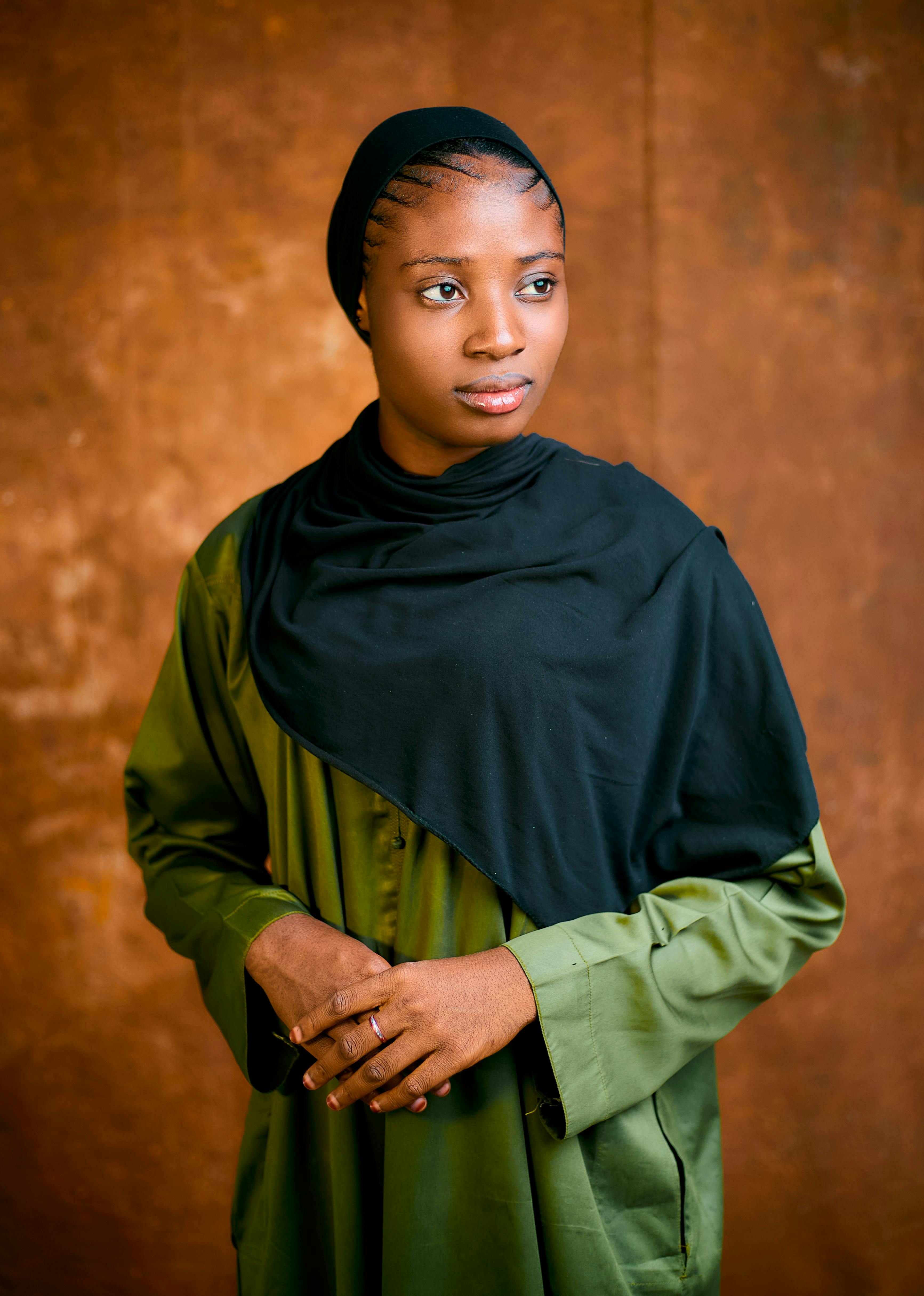 Kostenlos Porträt einer Frau mit Hijab und grünem Kleid vor strukturiertem Hintergrund. Stock-Foto
