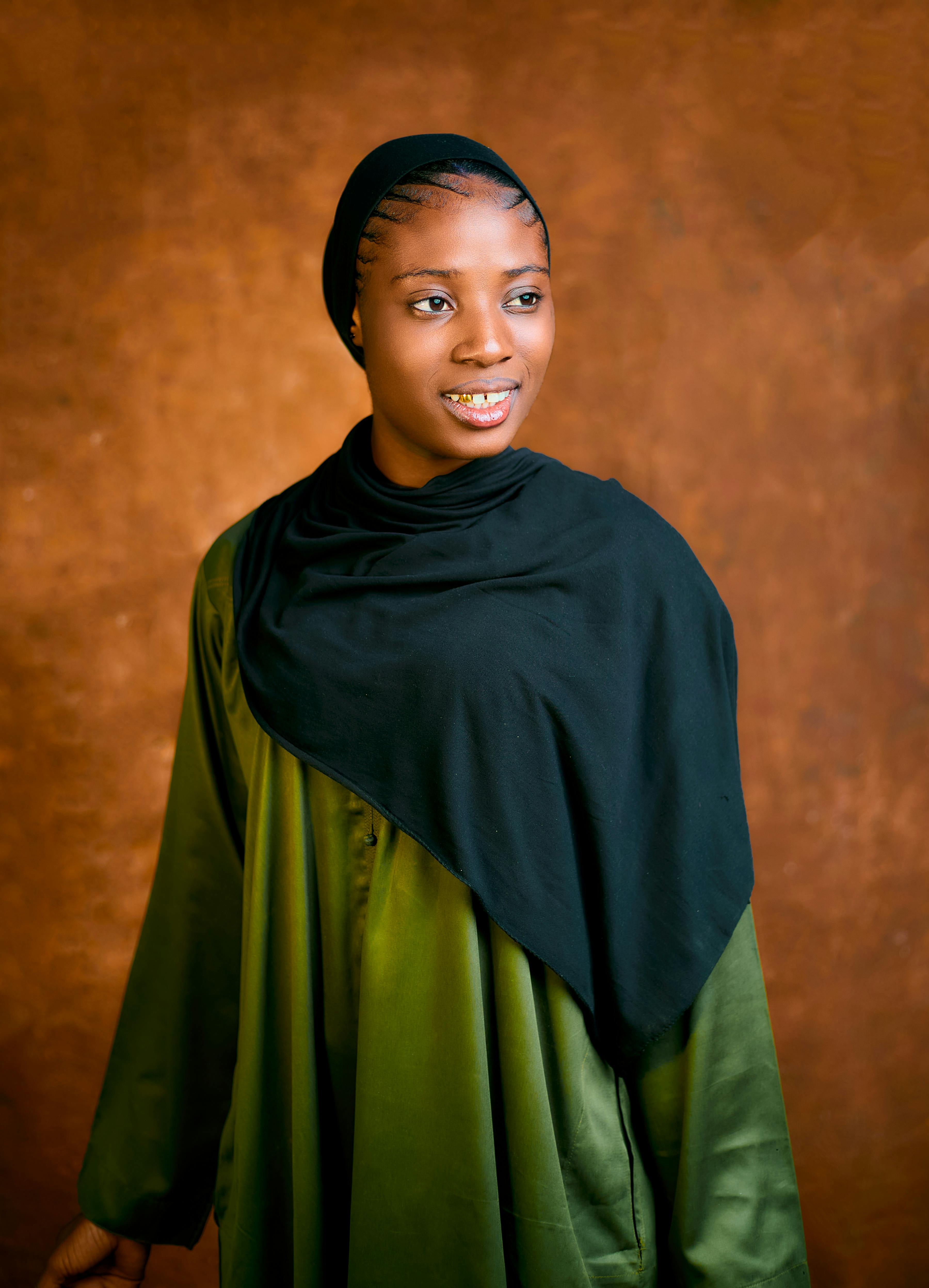 Kostenlos Elegantes Porträt einer Frau mit strahlendem Lächeln in traditioneller Kleidung vor einem strukturierten braunen Hintergrund. Stock-Foto