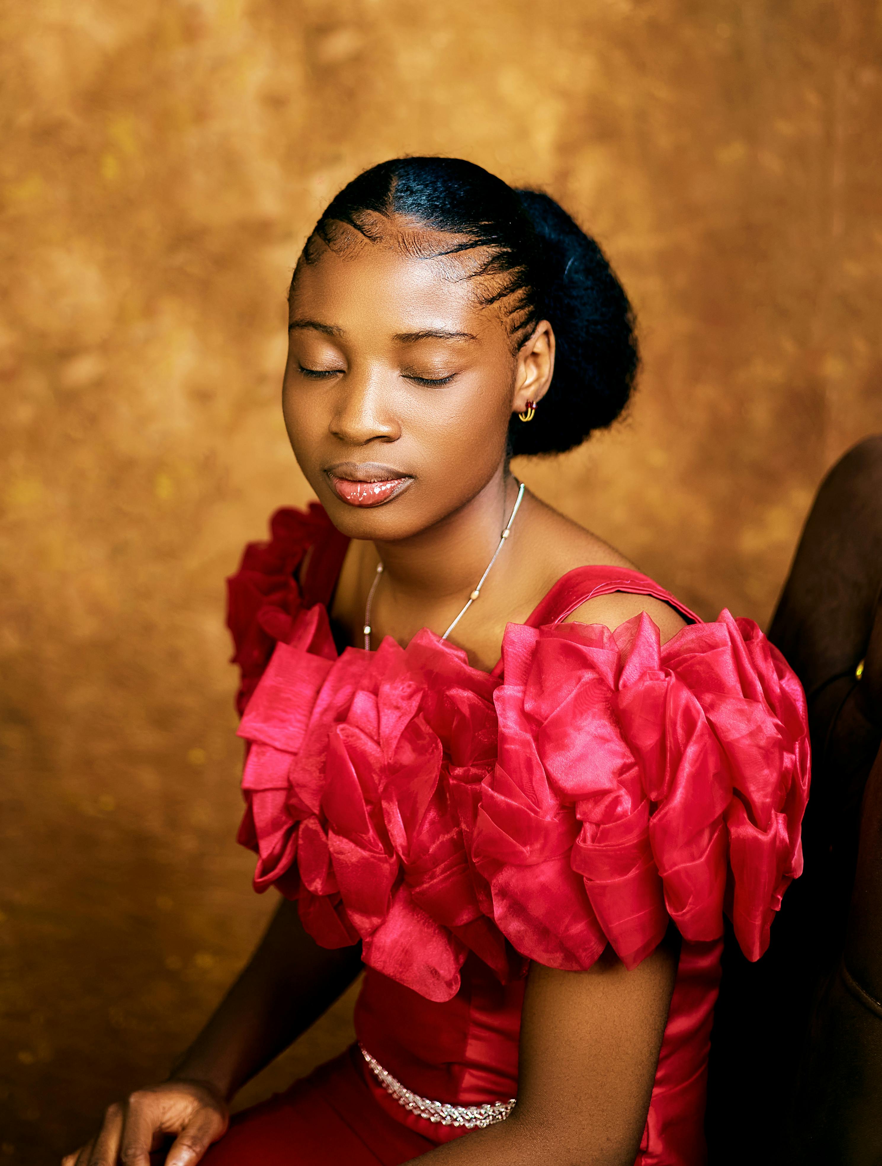 Gratis Rolig kvinne i rød formell kjole på en teksturert brun bakgrunn. Arkivbilde