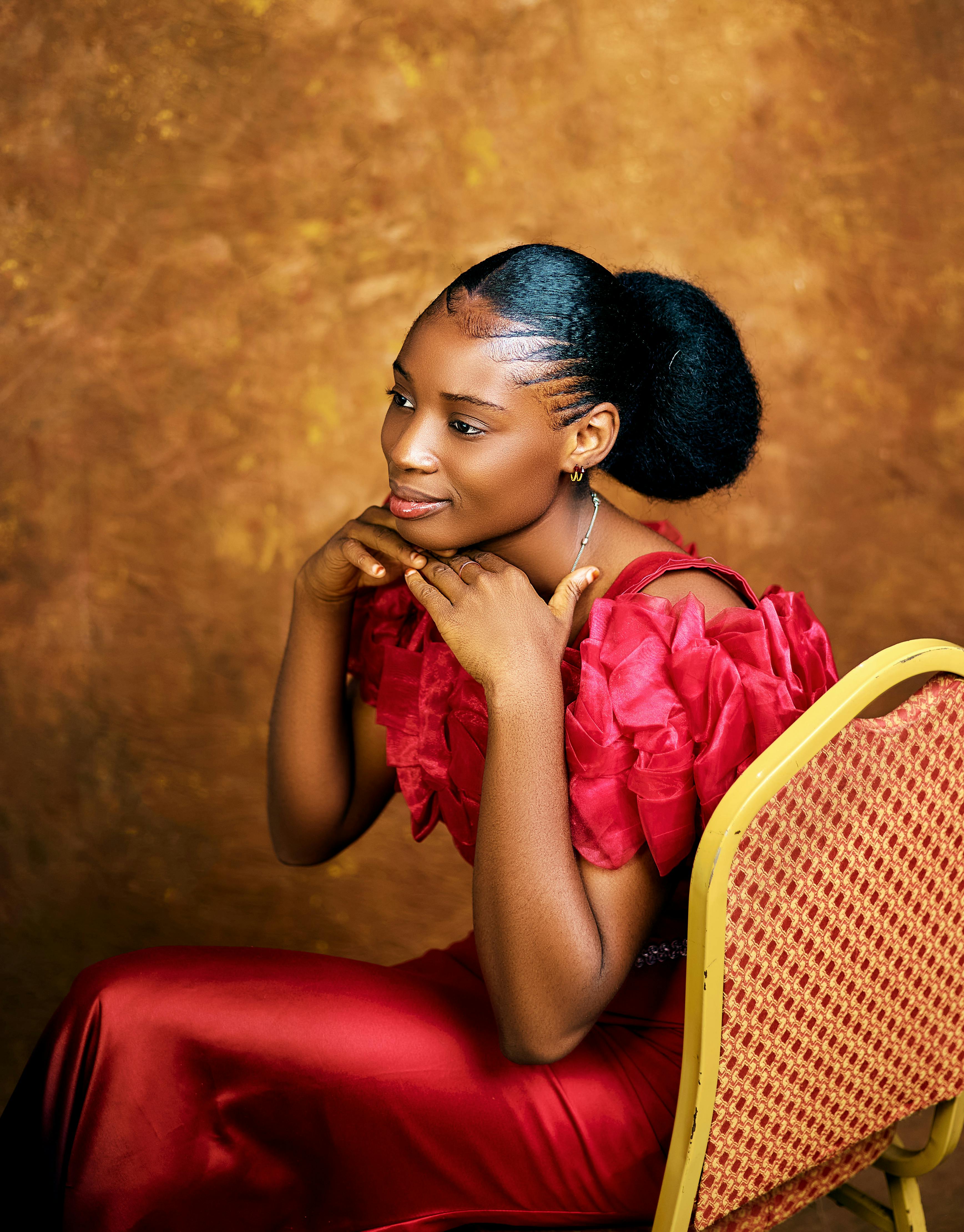 Kostenlos Stilvolles Porträt einer afrikanischen Frau in einem leuchtend roten Kleid vor einem satten braunen Hintergrund. Stock-Foto