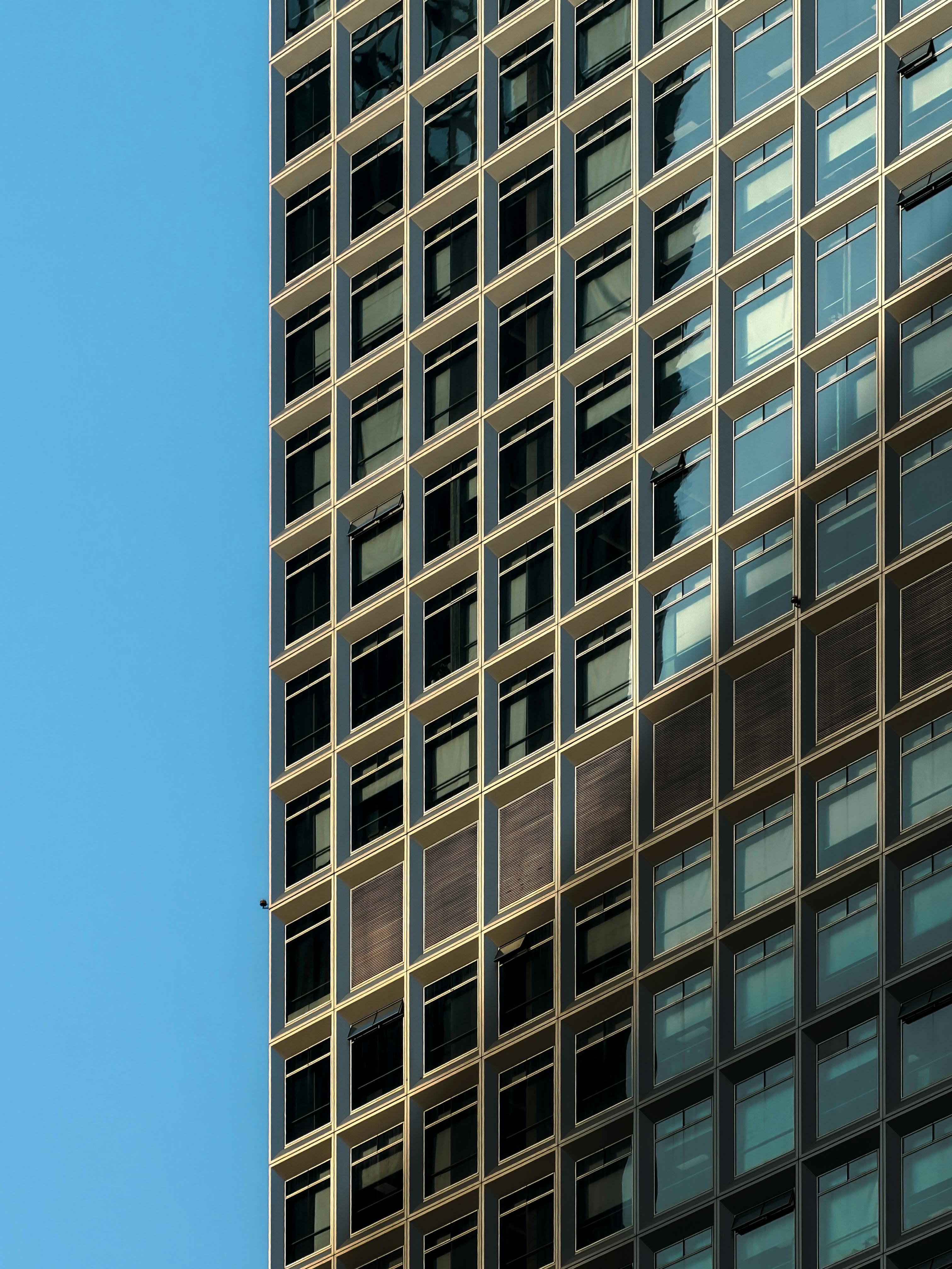 бесплатная Современный стеклянный фасад, отражающий солнечный свет в китайском городе, демонстрирует особенности городской геометрии. Стоковое фото