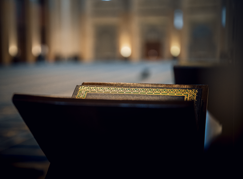 Free A beautifully blurred mosque interior with a Quran on a stand, creating a serene atmosphere. Stock Photo