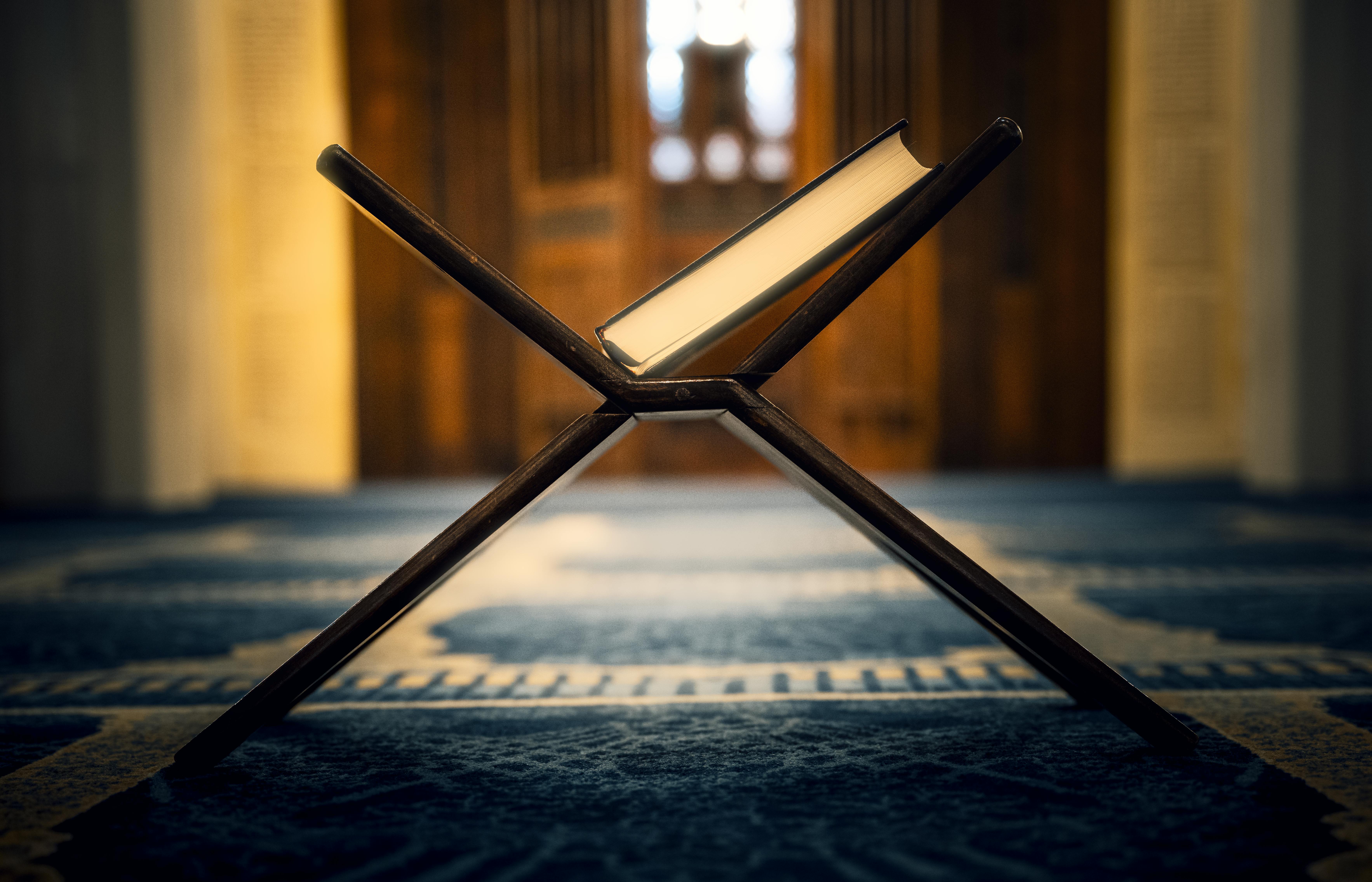 Δωρεάν Περίπλοκα σχεδιασμένη βάση για το Κοράνι μέσα σε ένα τζαμί με χαλί με σχέδια και απαλό φωτισμό. Φωτογραφία από στοκ φωτογραφιών