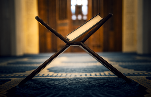 Free Intricately designed Quran stand inside a mosque with patterned carpet and soft lighting. Stock Photo