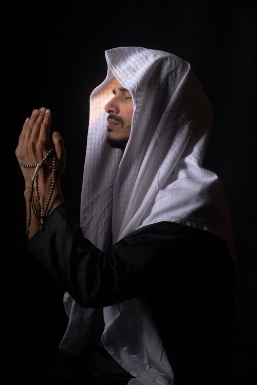 Man in Traditional Attire Praying with Rosary Beads · Free Stock Photo