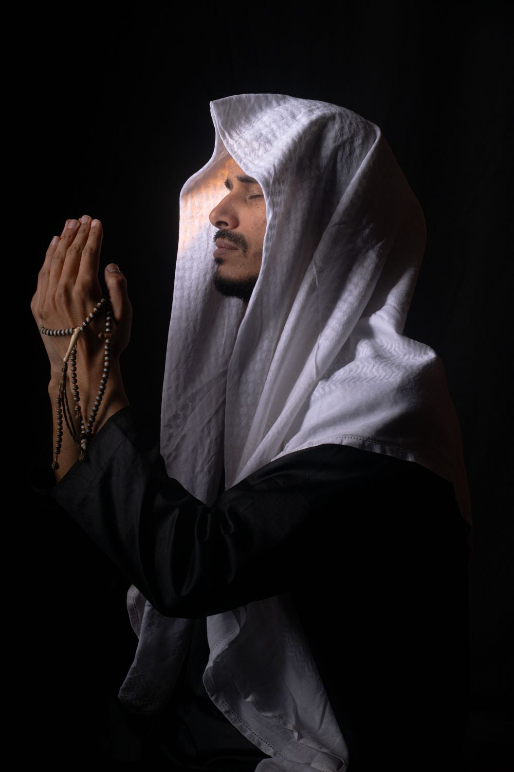 Man in Traditional Attire Praying with Rosary Beads · Free Stock Photo