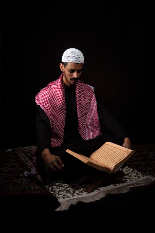 Free A man in traditional attire reading a religious text in quiet reflection. Stock Photo