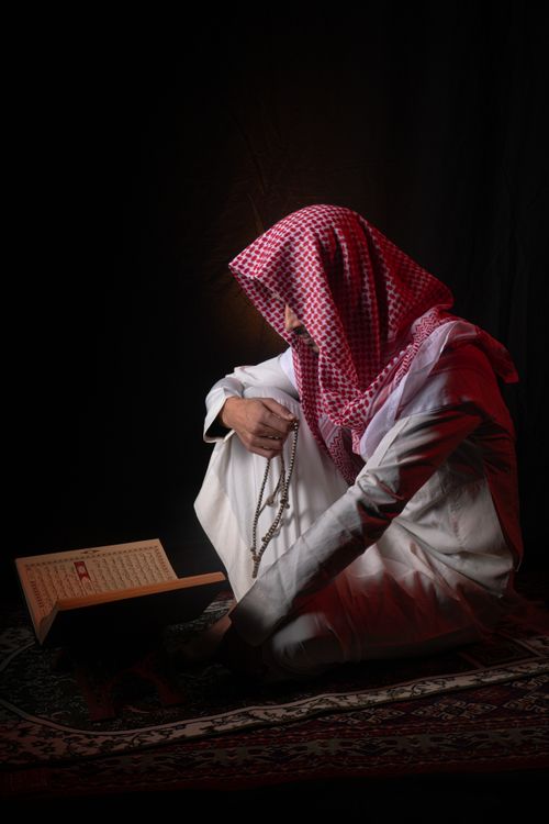 Man Praying with Rosary Beads in Traditional Attire · Free Stock Photo
