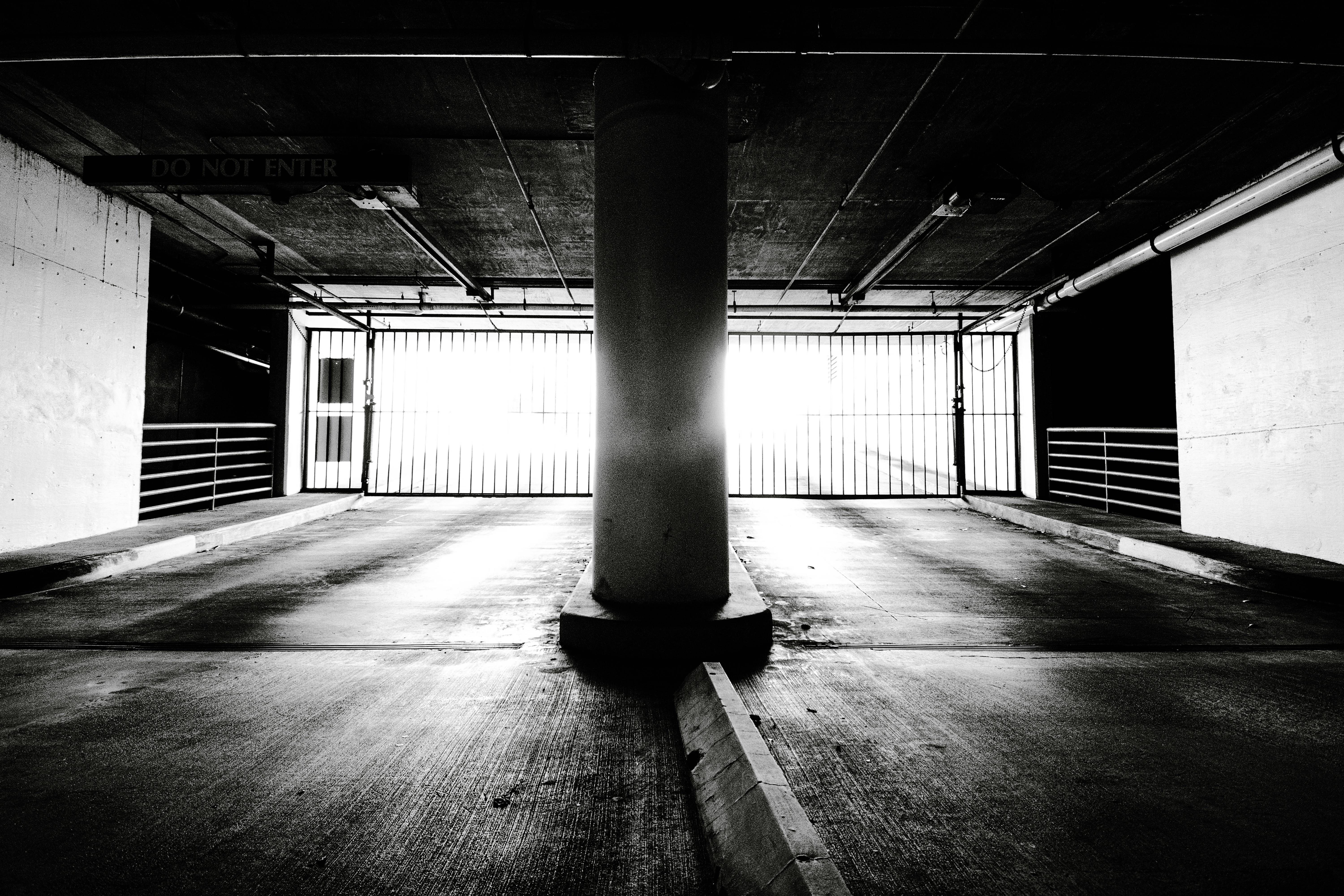 бесплатная Эффектная черно-белая фотография подземной парковки с ярким освещением на выезде. Стоковое фото