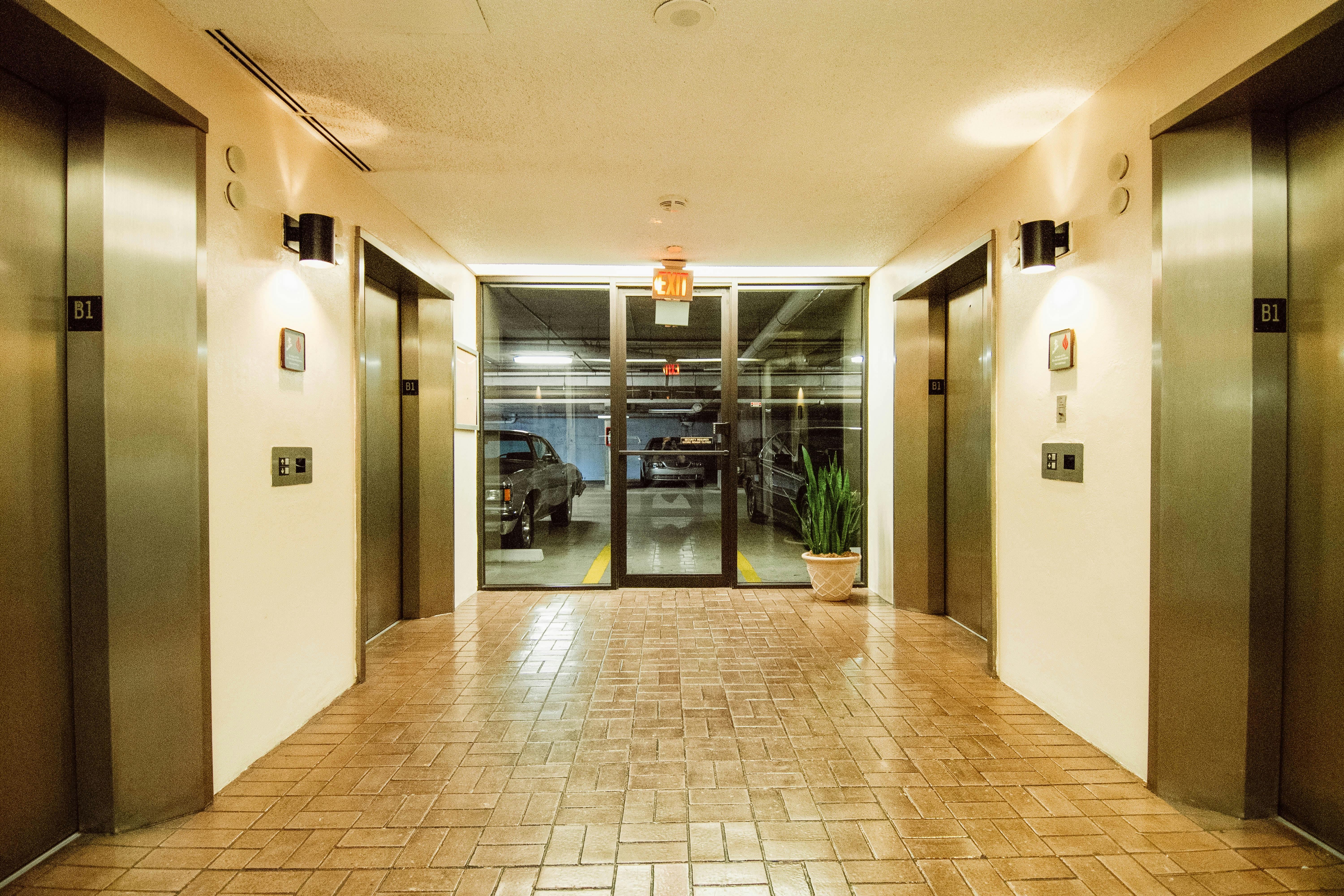 Δωρεάν Ένα καθαρό και καλά φωτισμένο λόμπι γκαράζ με πολλαπλούς ανελκυστήρες και πινακίδα εξόδου. Φωτογραφία από στοκ φωτογραφιών