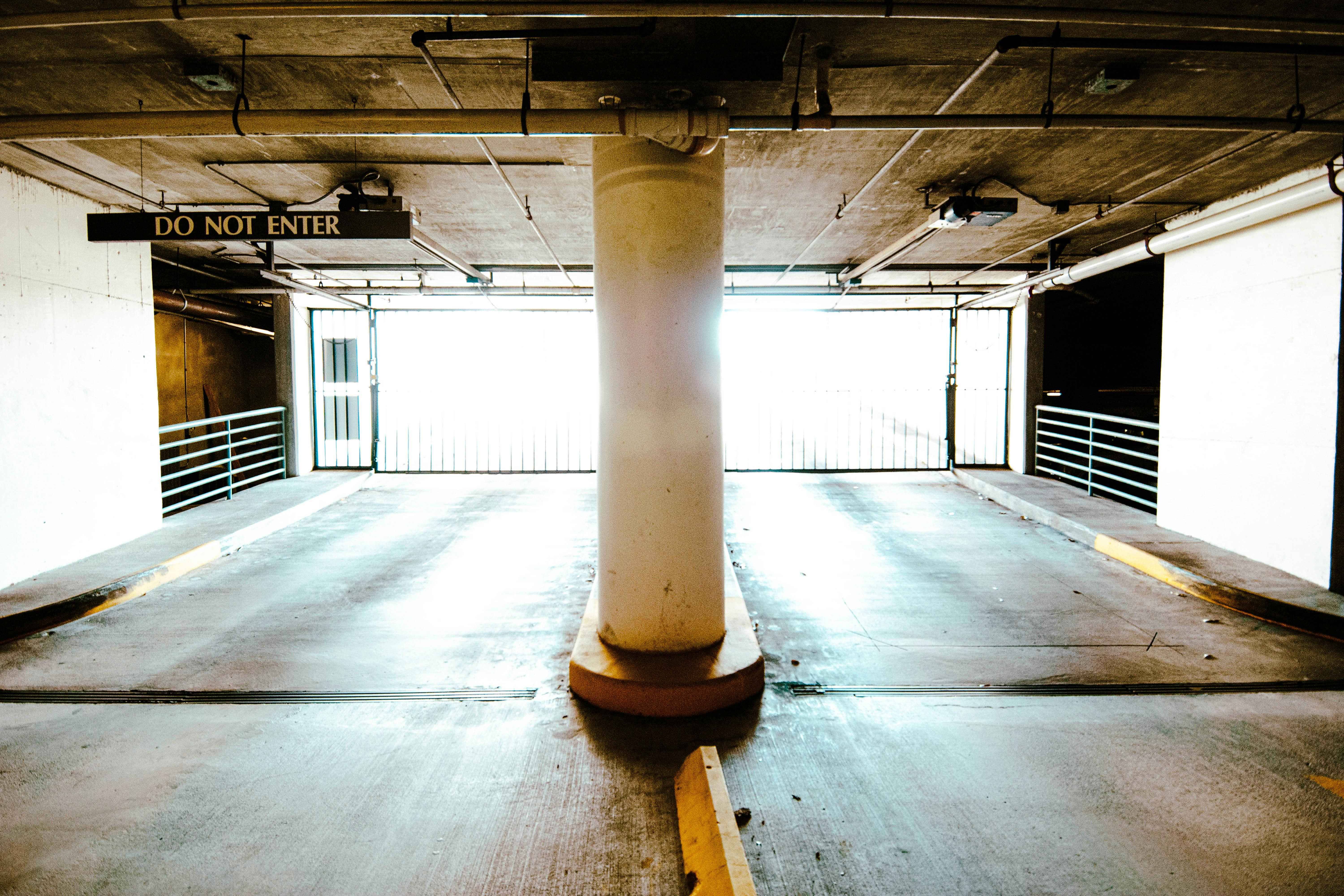 無料 中央の柱と「進入禁止」の標識がある、明るく照らされた空の駐車場。 写真素材