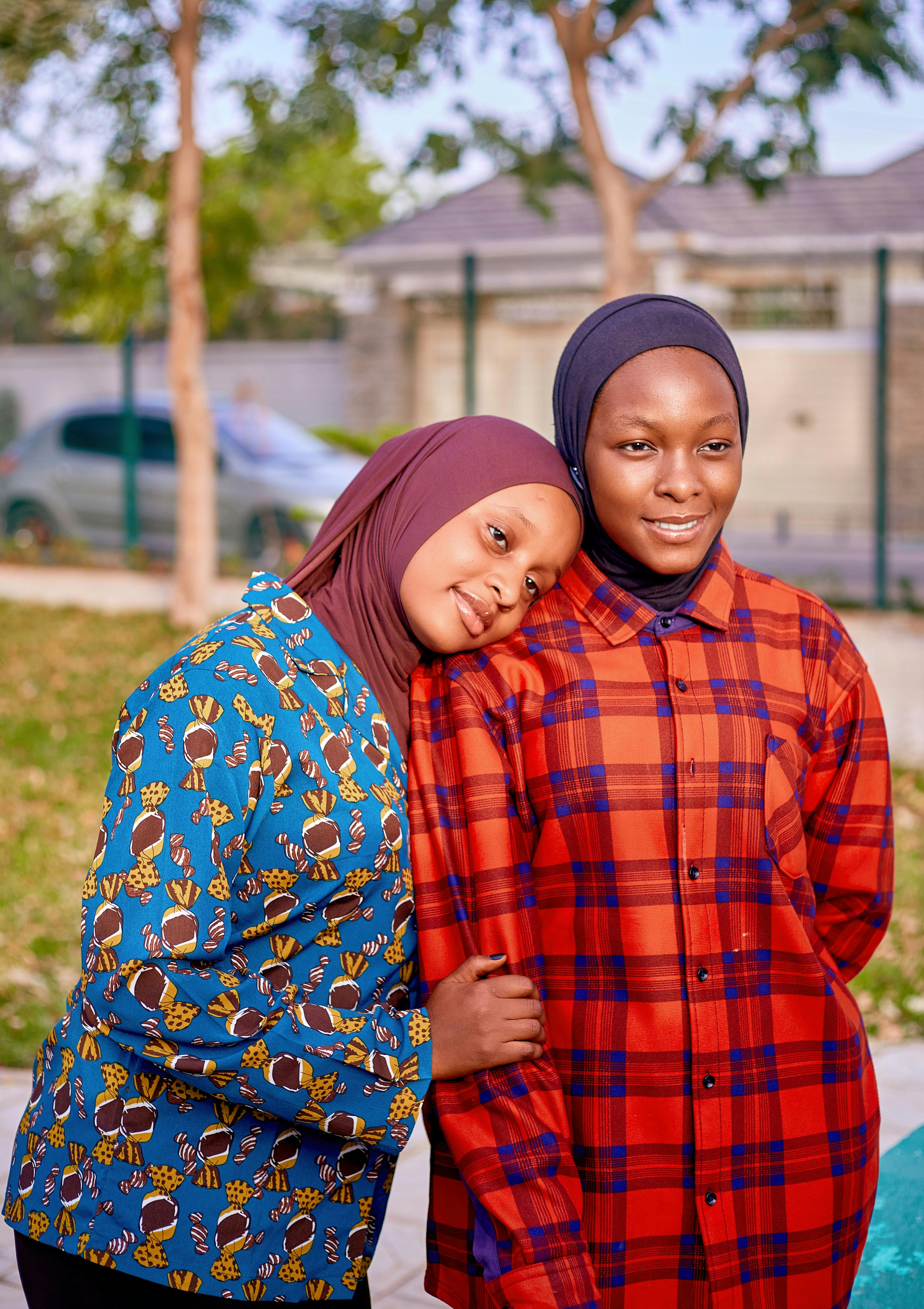 Kostenlos Zwei junge Frauen in farbenfrohen Hijabs und lässigen Hemden genießen einen Moment im Freien. Stock-Foto