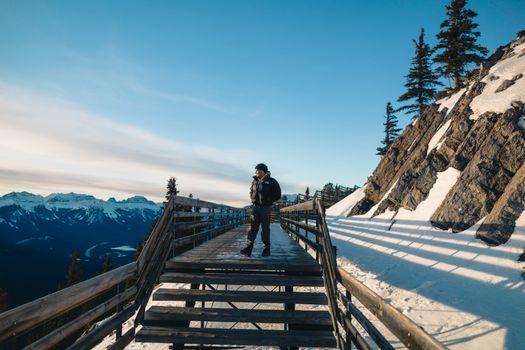 Man enjoying a scenic hike on a snowy boardwalk in Banff National Park.