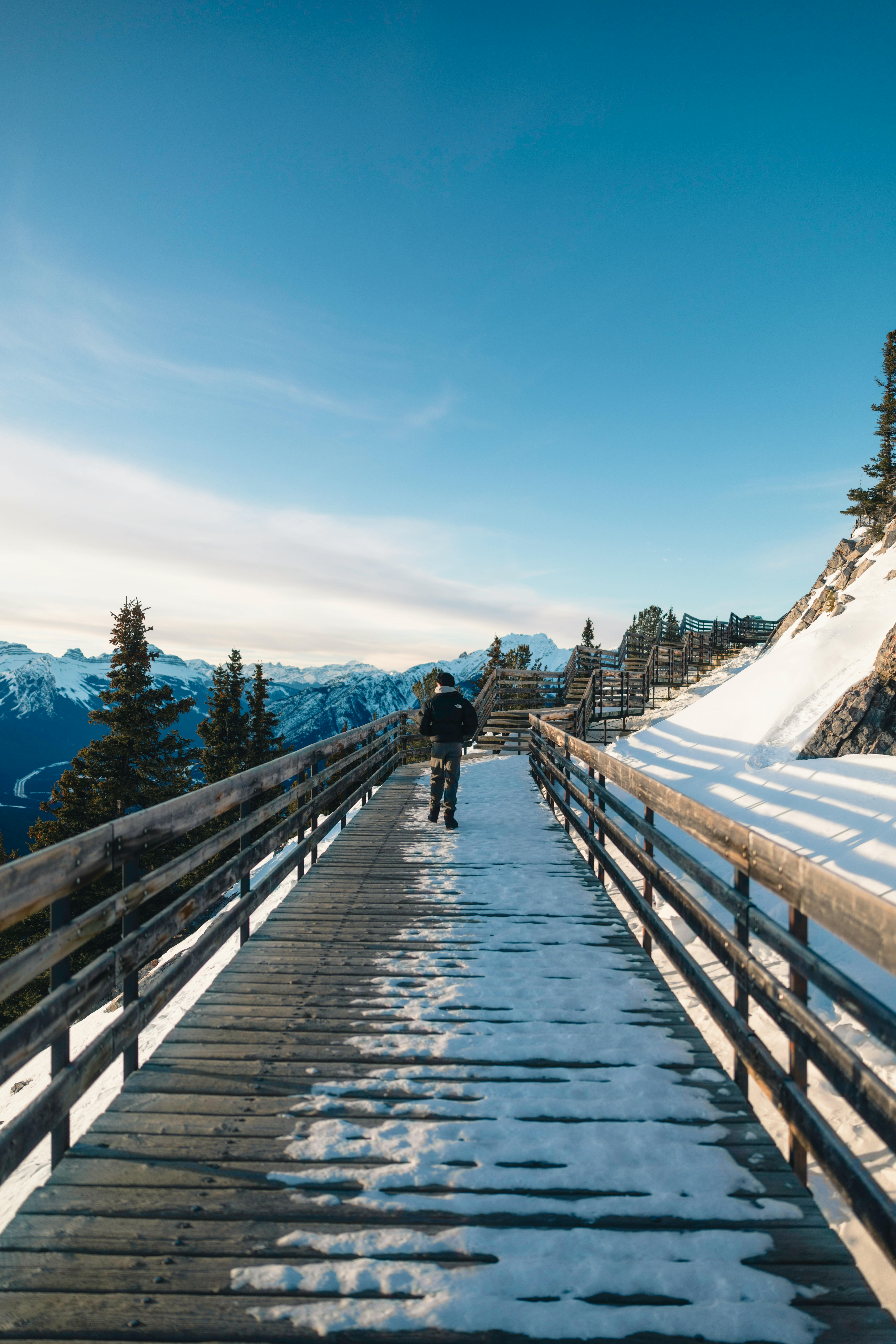 Kostenlos Erkunden Sie den malerischen, schneebedeckten Holzsteg im Banff-Nationalpark mit Blick auf die Berge. Stock-Foto