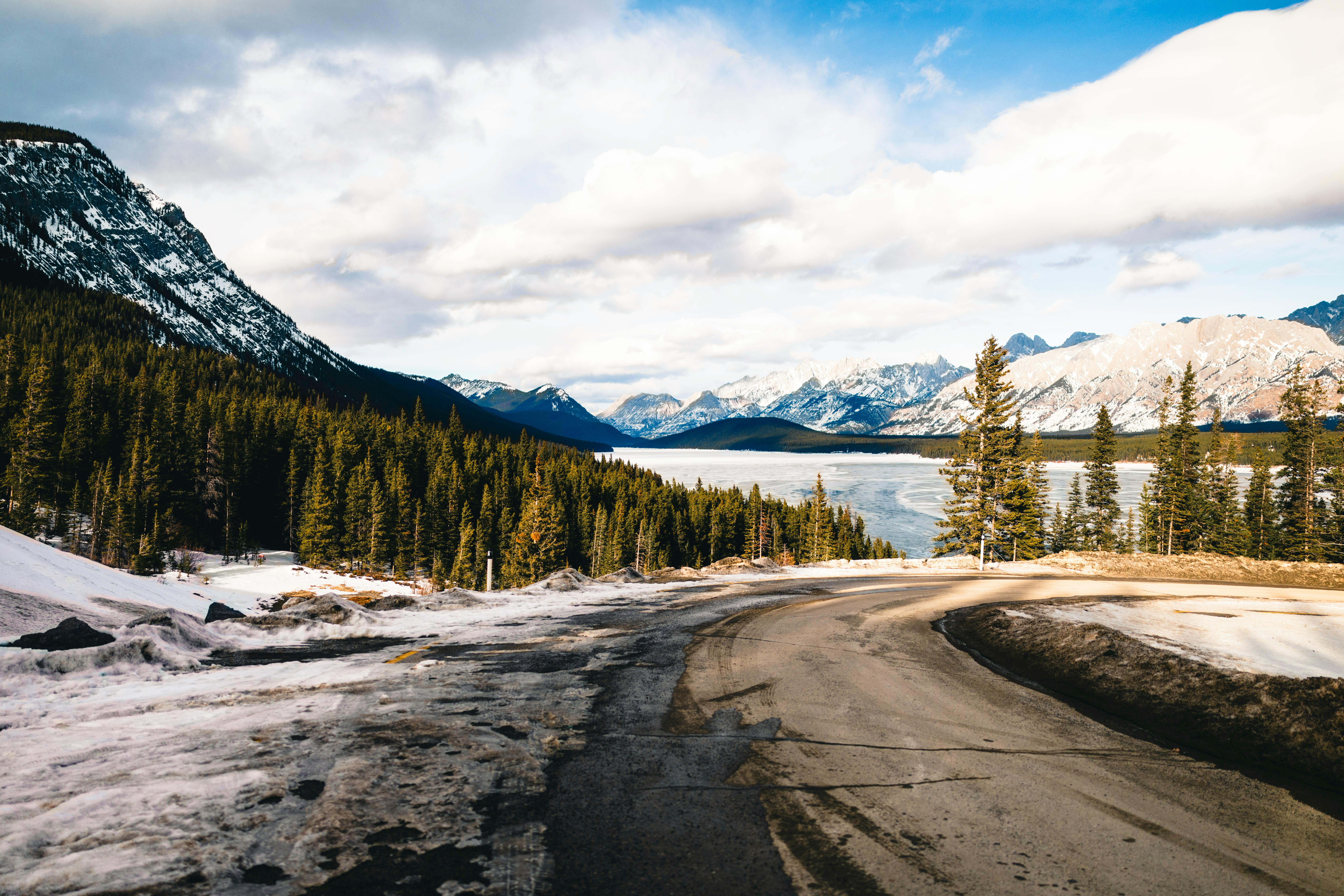 Kostenlos Faszinierende Winterlandschaft im Banff-Nationalpark mit schneebedeckten Bergen und einer kurvenreichen Straße. Stock-Foto