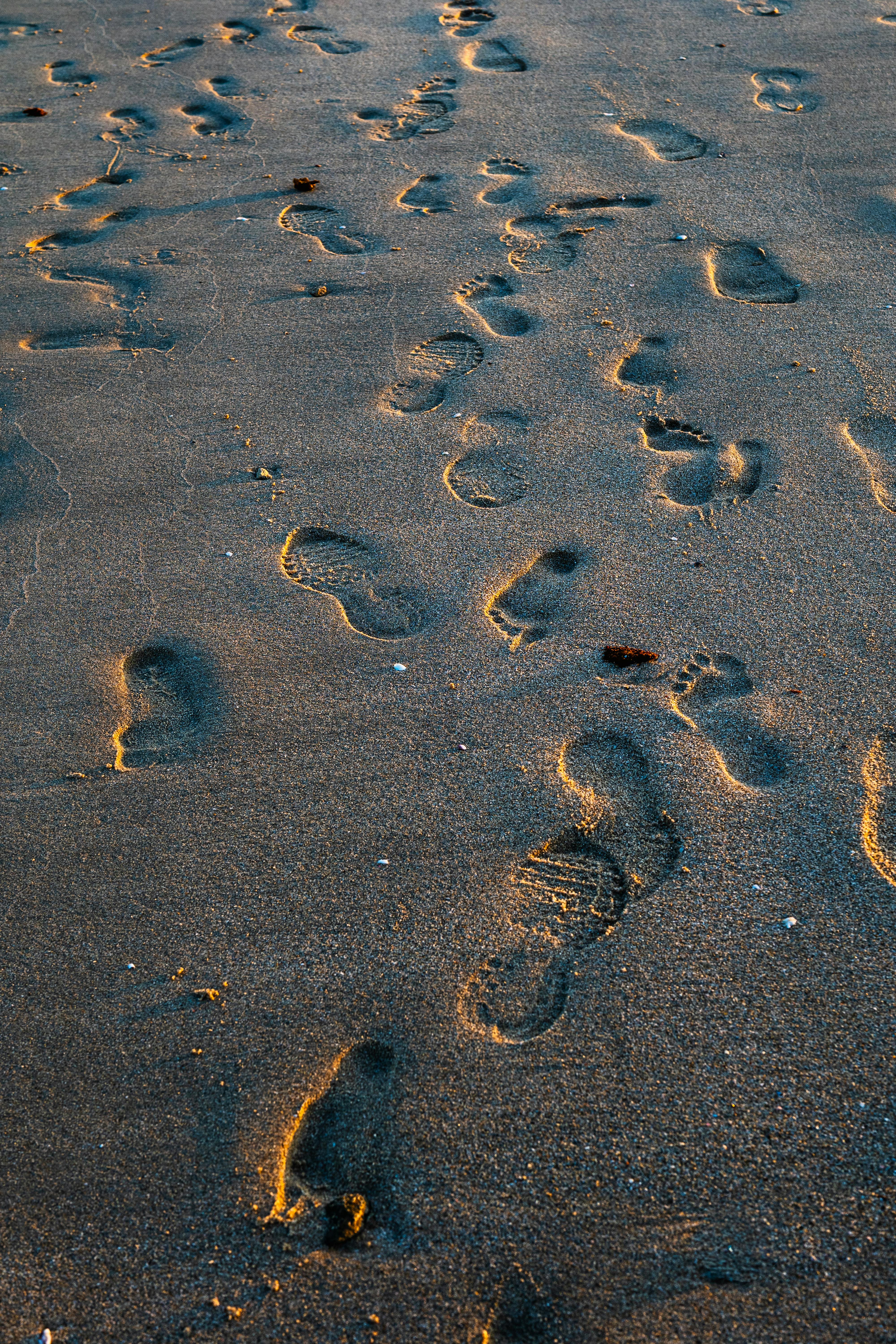 Δωρεάν Ίχνη πατημασιών διασχίζουν μια αμμώδη παραλία κατά το ηλιοβασίλεμα, αποτυπώνοντας την ηρεμία μιας παραθαλάσσιας βόλτας στο Κουβέιτ. Φωτογραφία από στοκ φωτογραφιών