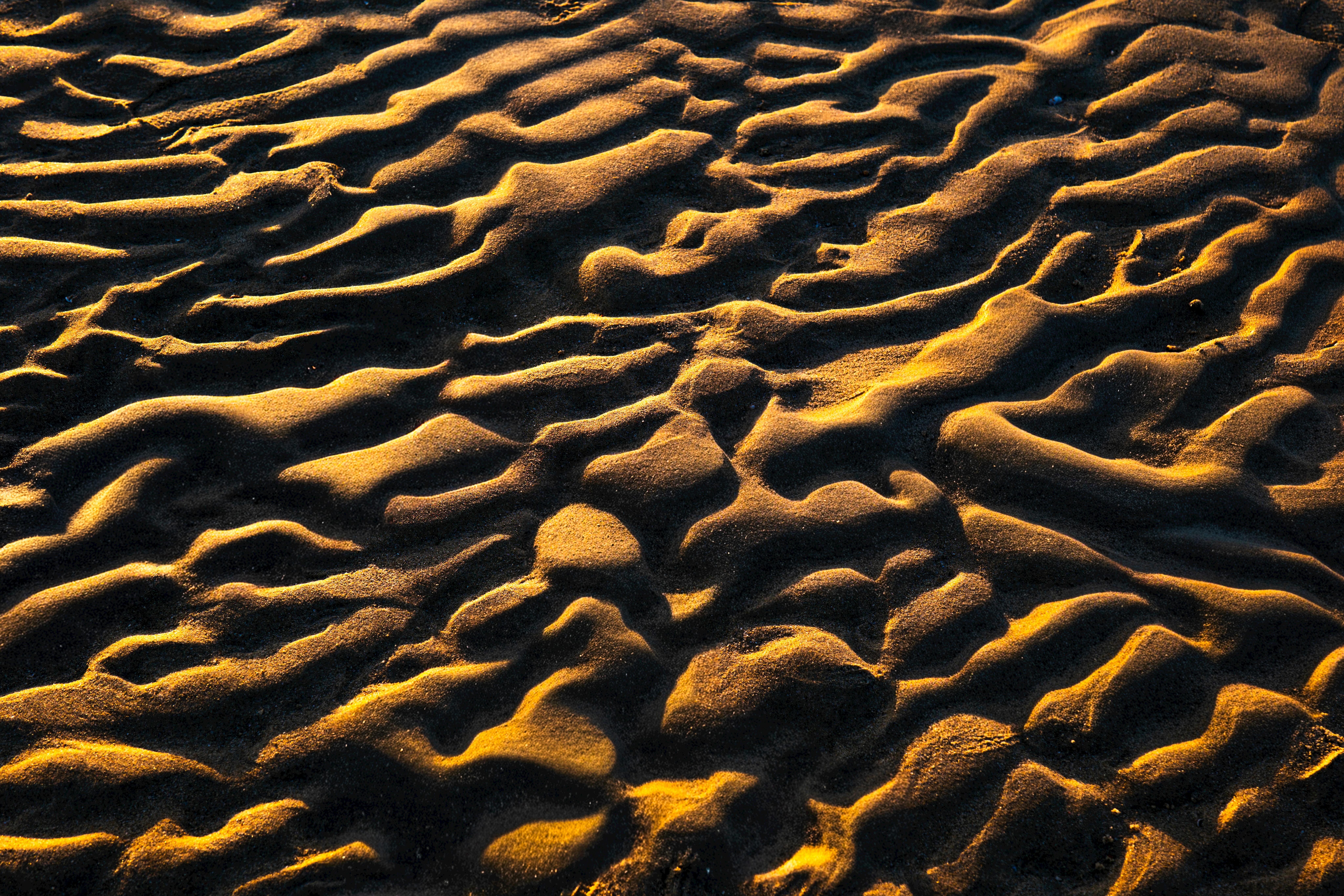 Kostenlos Aufnahme von sonnenbeschienenen Sandmustern, die eine markante abstrakte Textur an einem Strand in Kuwait erzeugen. Stock-Foto