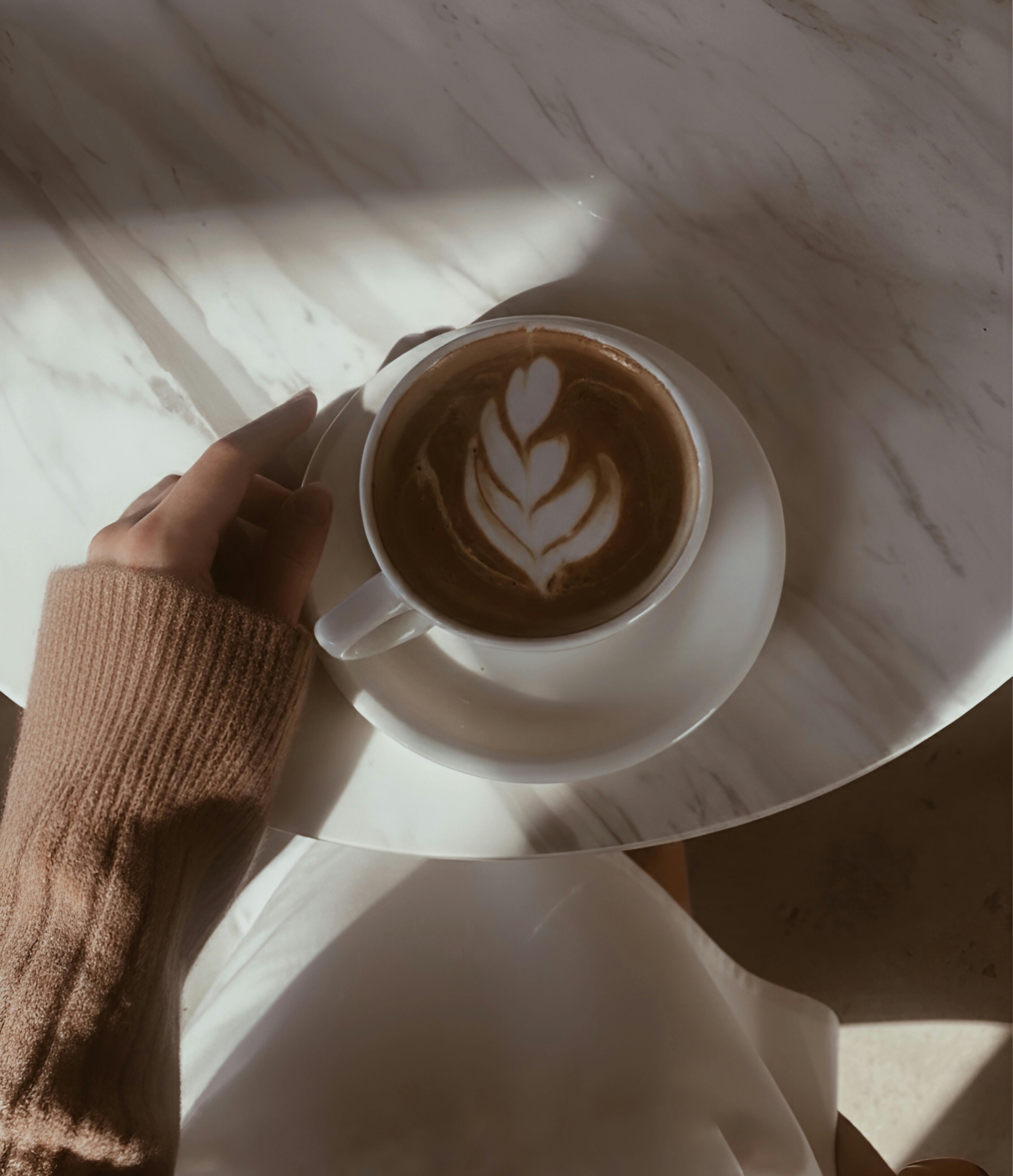 Free A cozy scene of a cappuccino with latte art in a warm setting. Stock Photo