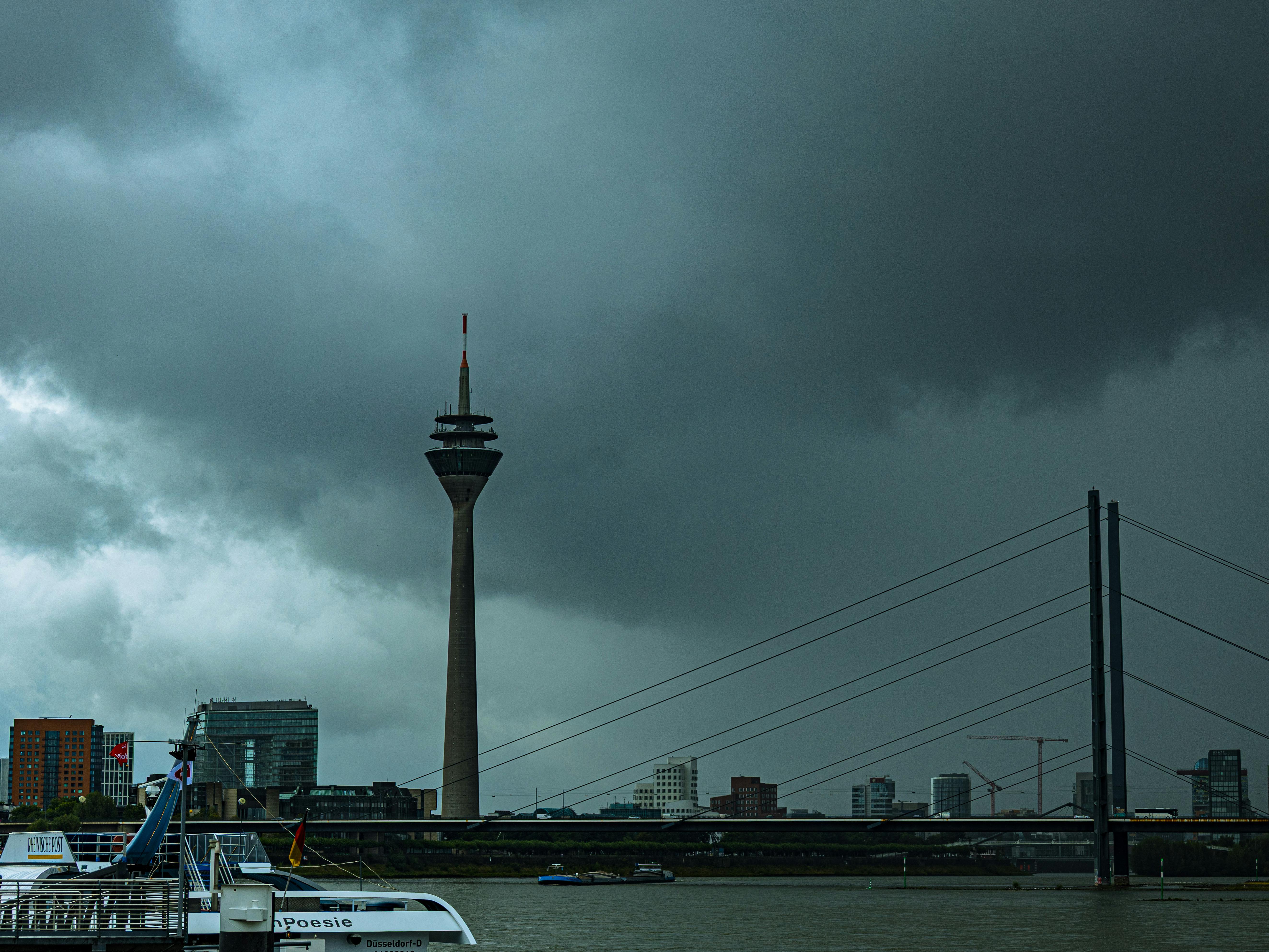 Gratis Stemningsfuld udsigt over Düsseldorfs skyline med den ikoniske Rheinturm mod en stormfuld himmel. Lagerfoto