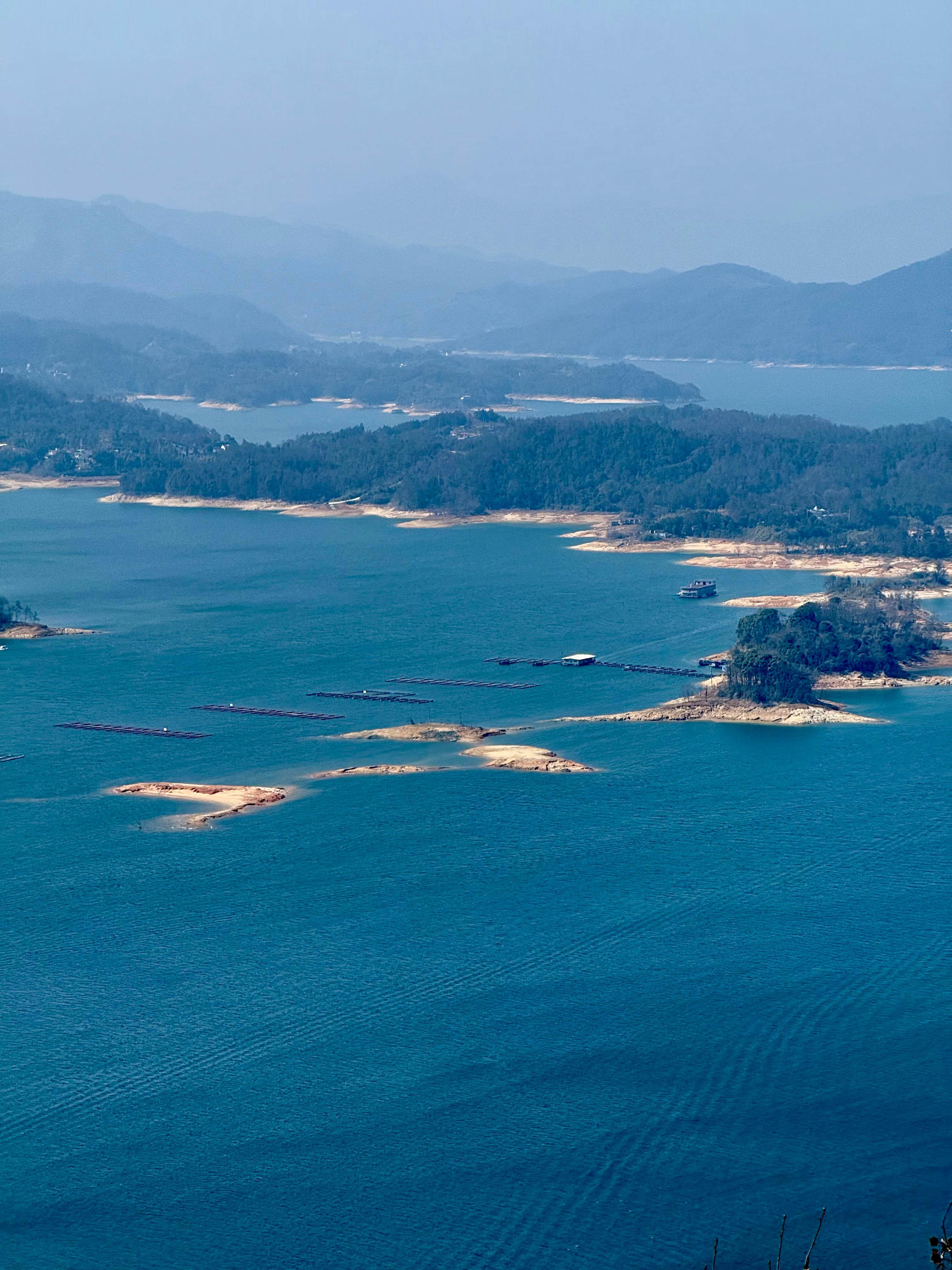 Kostenlos Atemberaubender Blick auf einen weitläufigen See mit kleinen Inseln und fernen Bergen unter klarem Himmel. Stock-Foto