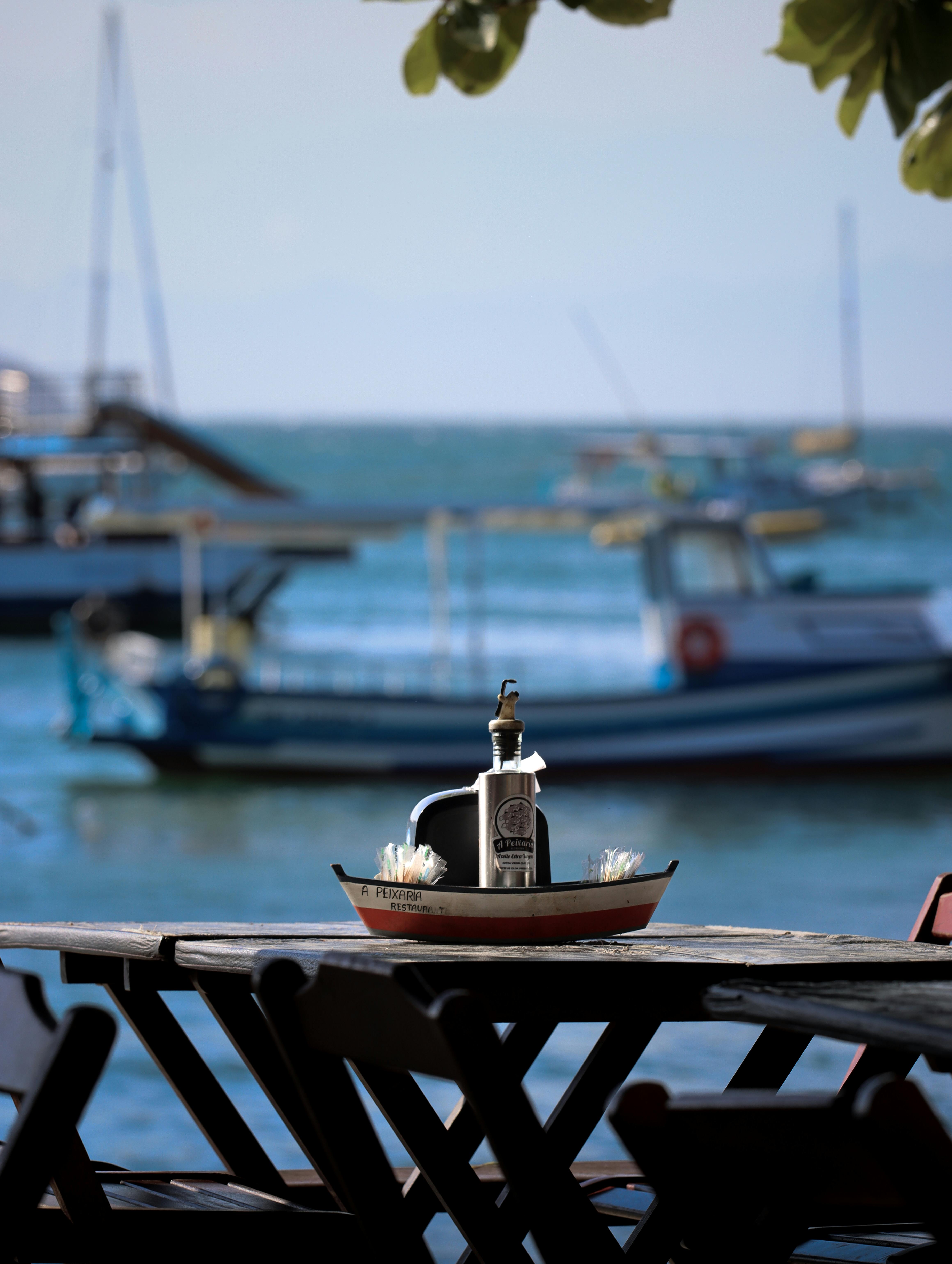 Kostenlos Charmante Tischdekoration am Meer mit maritimen Motiven und Blick auf Boote an einem sonnigen Tag. Stock-Foto