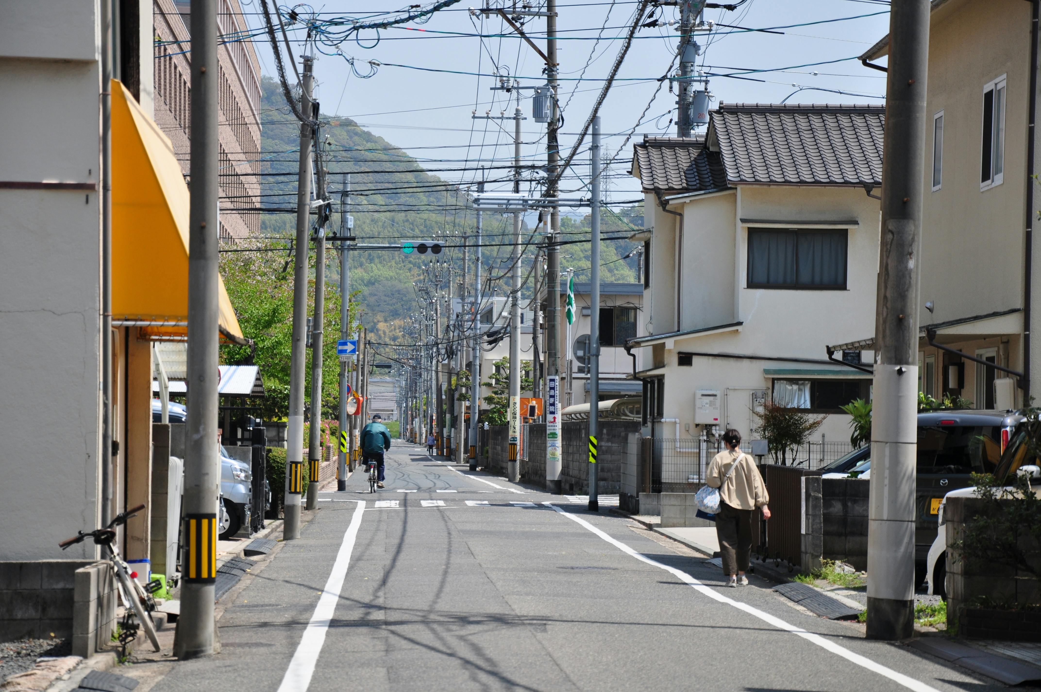 Δωρεάν Μια γαλήνια προαστιακή σκηνή δρόμου στην Ιαπωνία με ανθρώπους να περπατούν και να κάνουν ποδήλατο. Φωτογραφία από στοκ φωτογραφιών
