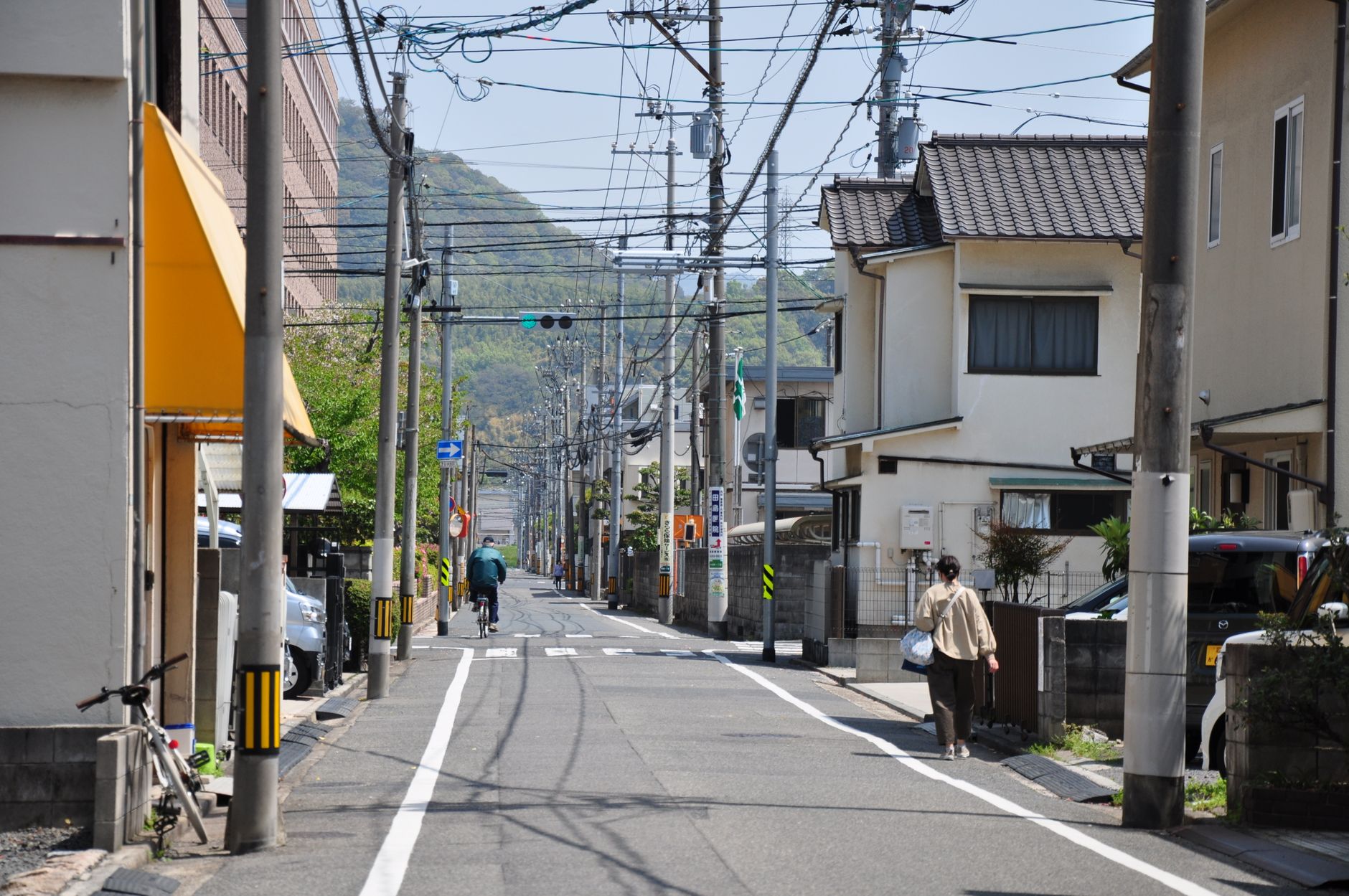 A serene suburban street scene in Japan with people walking and biking.