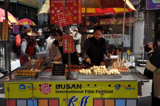 Vibrant street food stall at Busan International Film Festival serving skewers.