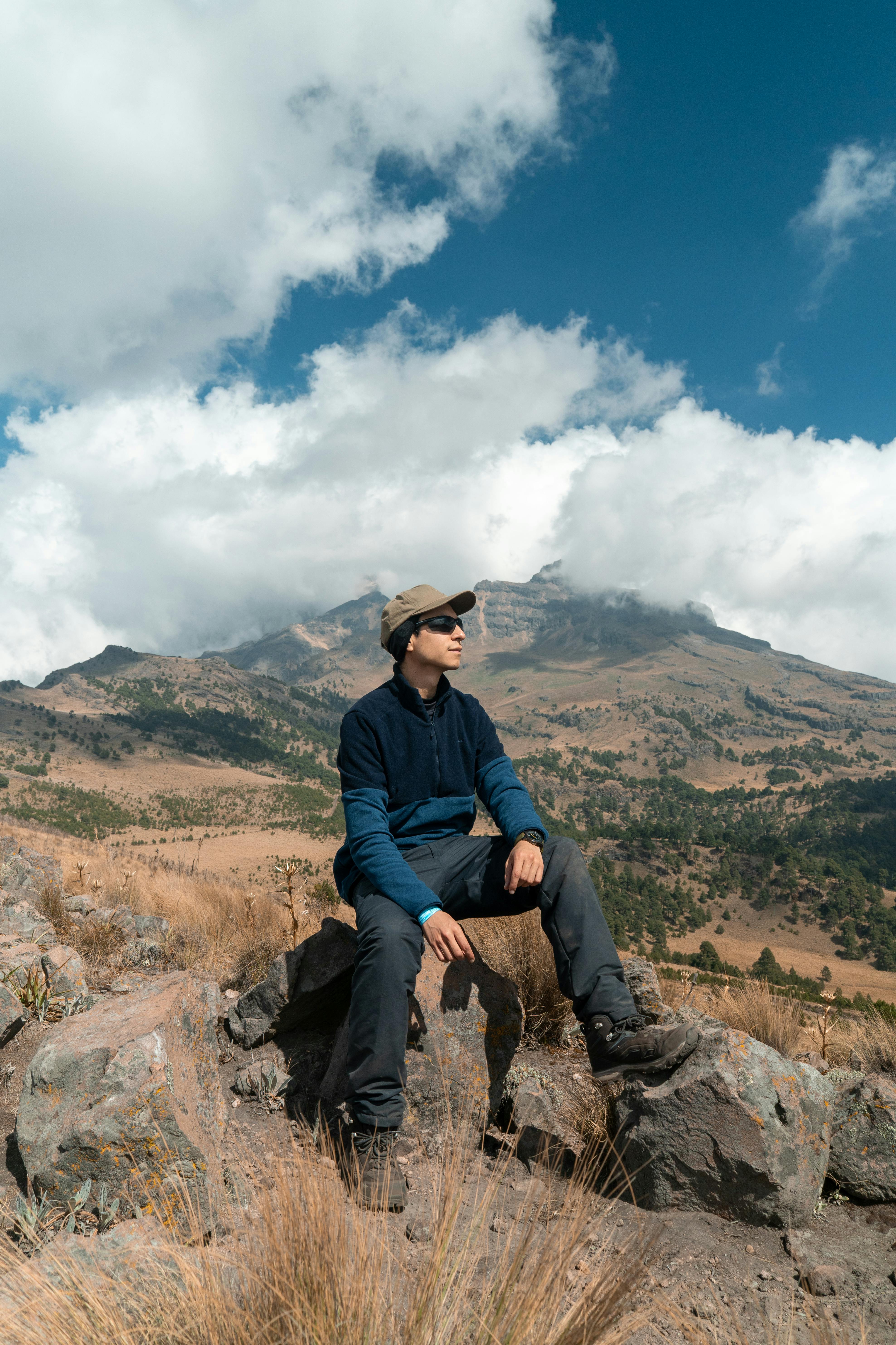 Kostenlos Entdecker auf einem felsigen Berggipfel mit malerischer Aussicht und strahlend blauem Himmel. Stock-Foto
