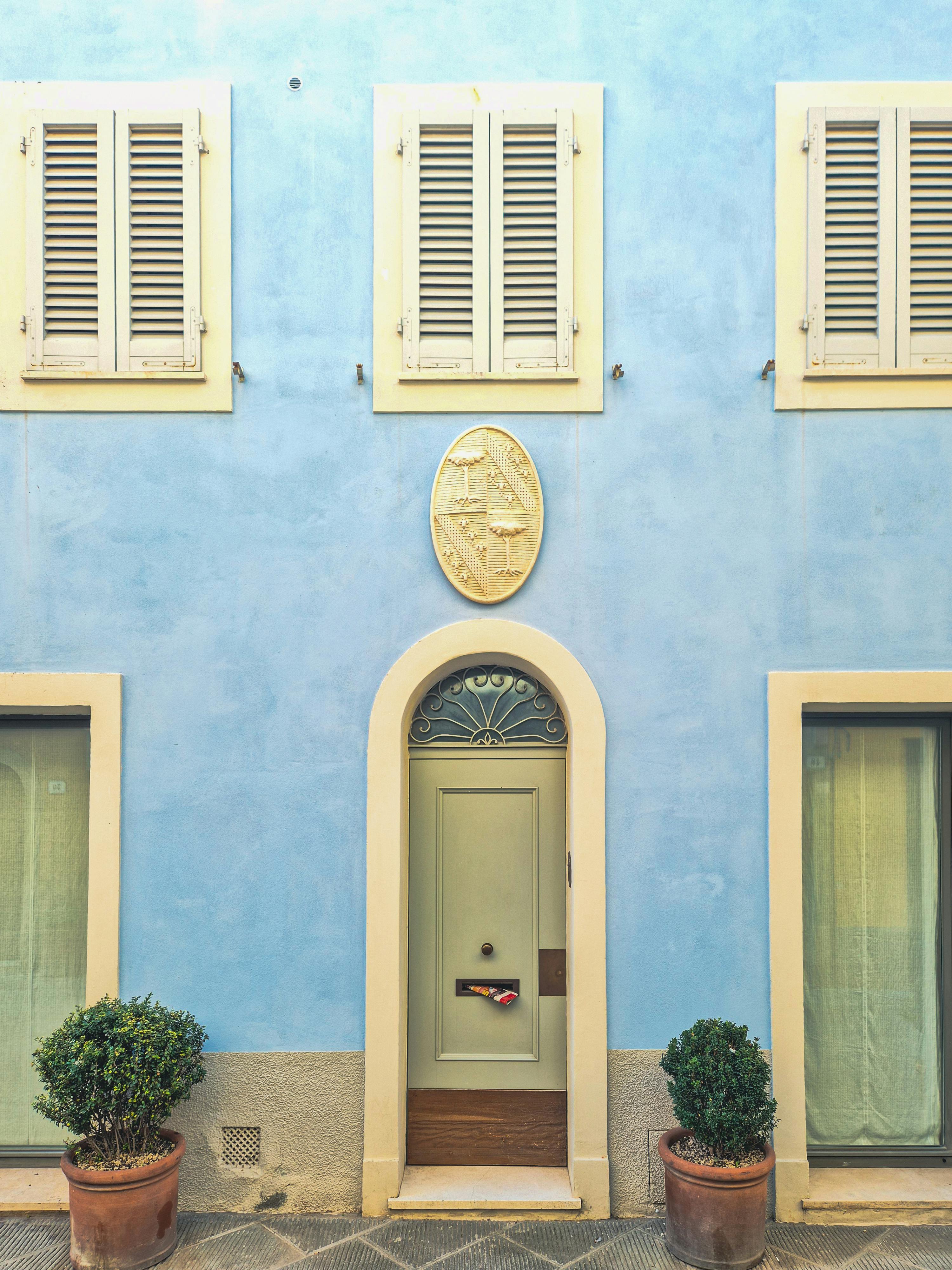 Gratuit Une façade européenne classique avec des murs bleus, une porte verte et des volets blancs décoratifs. Photos